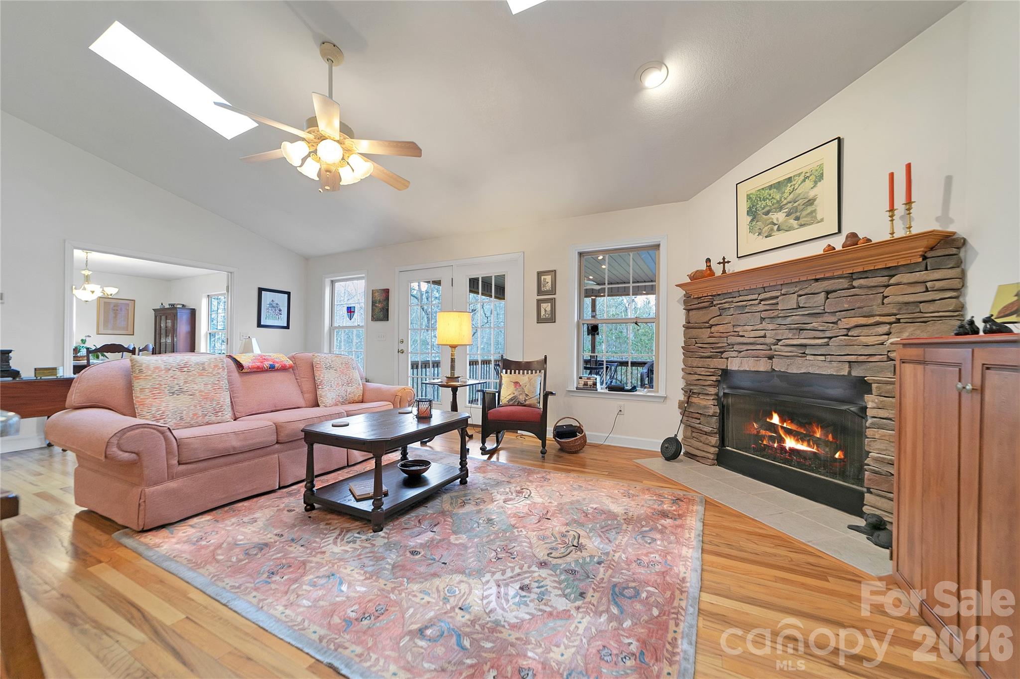 Drive up to your new home, on the level cobblestone driveway surrounded by native plants and mature woods, to this beautifully maintained, peaceful retreat tucked away at the end of a cul-de-sac on a rare double lot in Connestee Falls. Built in 2002 and lovingly cared for by its original owners, this home offers a gracious, welcoming layout ideal for both entertaining and quiet evenings by the fireplace with your favorite book. The spacious dining room is filled with natural light and overlooks acres of serene common-area forest, creating a lovely backdrop for everyday meals or special gatherings. Step outside to enjoy the recently upgraded outdoor living spaces, featuring all-new high-end composite decking and an open deck just off the screened porch. Inside, the remodeled kitchen shines with beautiful granite countertops, an added coffee bar, additional cabinetry, and matching new cabinets in the laundry room. Bathrooms have also been updated with Silas stone vanity tops. The basement offers an insulated workshop area, an exterior door leading to a level graveled space beneath the screened porch, and an easily accessible crawlspace providing ample storage.