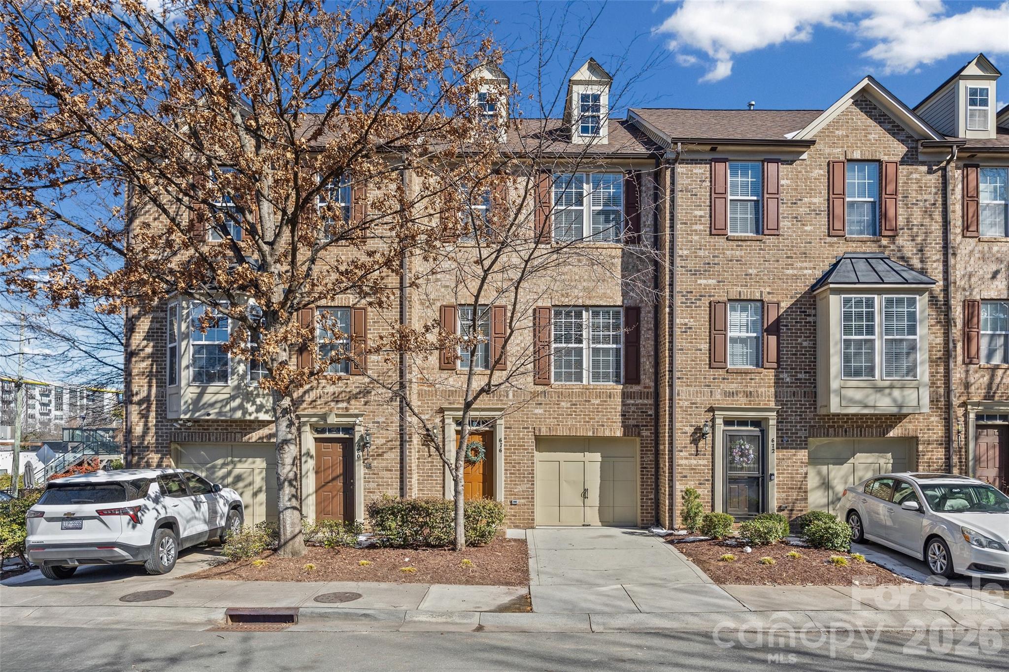 Rare South End townhome built for modern city living—walkable, move-in ready, and flexible enough for working from home without sacrificing space or style. This 4-bedroom townhome offers the space you want with the connected, lock-and-leave lifestyle today’s buyers demand, all in the heart of one of Charlotte’s most vibrant neighborhoods. Fresh interior paint and brand-new carpet throughout make it easy to unpack and enjoy from day one. The kitchen is designed for both everyday living and entertaining, featuring granite countertops, stainless steel appliances, and a gas range with double convection oven. The light-filled main level showcases hardwood floors, a gas-log fireplace, and a sunroom with dry bar—perfect for hosting friends or unwinding after a long day. Upstairs, the third level features a spacious primary suite plus two additional bedrooms. The first-floor bedroom with a large walk-in closet offers exceptional flexibility, ideal for a home office, guest suite, or media room. Major system updates include a new HVAC (9/2025) and a new roof (2025), providing peace of mind and low-maintenance ownership. Washer, dryer, and refrigerator convey.
A one-car garage with additional driveway and street parking adds everyday convenience. Step outside to enjoy unbeatable access to the Blue Line light rail, award-winning restaurants, breweries, shops, and Uptown. Walk to Panthers games or Knights games, skip the commute, and live where work, play, and connection come together. Urban, effortless, and move-in ready—this is South End living at its best.