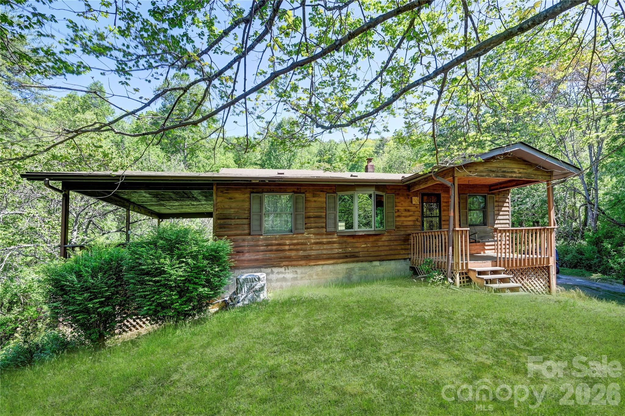 This Home Sits on 2.33 Acres close to 'All Things South Asheville'. It is nearly move-in ready; just add kitchen appliances. The possibilities are endless; First Time Homebuyers, Downsizers, or as a Short or Long Term Rental Property. The 'Very Large Lot' sets this property apart from Anything Else You'll Find in This price range. There are 3 different outdoor covered areas to enjoy the Peace & Solitude. Dine or Lounge on the Large Covered Deck off of the living room, Swing on the Covered Front Porch Swing, or enjoy the Backyard View from the Covered Back Patio. The floorplan is 'Open Concept' Living room, Dining area, and Kitchen; with a nice Bay Window in the Living area for growing plants indoors year round. A nice big Laundry Room is located right off of the Kitchen with Plenty of Storage area. There are 2 bedrooms and one full bath; with everything on one level. There is a tall crawlspace with room for additional storage under the home. An abundance of outdoor space for gardening, pets or just enjoying nature, with an outbuilding for your lawn and garden supplies. With 2.33 acres it is possible you may even be able to add another home; but this would need to be confirmed by buyers.
