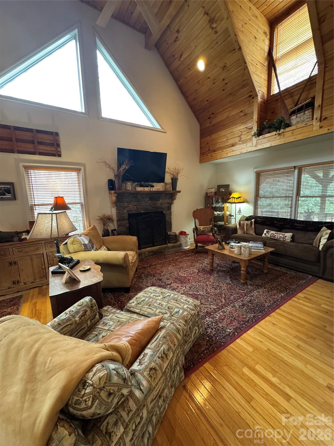 From the moment you step through the front door, you’ll be drawn to the stunning tongue-and-groove vaulted ceilings, ample windows and the stone gas log fireplace. Seamlessly creating the mountain atmosphere you’ve been searching for. The open-concept main living area features a comfortable living room that flows into the kitchen and dining area where the bar offers additional seating. The main-level primary bedroom has an en suite bathroom with large soaking tub and separate shower. For convenience this level also offers a half bath just off the living room area. The upper loft offers a spacious open concept, housing the second bedroom and a full bath, providing comfort and privacy for guests. The lower level presents endless possibilities, currently featuring a large den, a third bedroom, a full bath, with potential for a game room. This level also provides access from the golf cart garage/workshop, with access to the exterior of the home. Step outside and be captivated by the expansive outdoor decking and entertaining space offering outdoor dining area, firepit area and much more! Here you can enjoy the beautiful mountain surroundings. The home also boasts a large covered front porch with wraparound access, ample parking, and convenient drive-through driveway access. While the garage accommodates a golf cart and includes a workshop area, please note it is not sized for a full vehicle. Only a compact. The home’s heating and air system requires repair; however, supplemental electric heat and propane gas logs are in place. Don’t miss the opportunity to view this unique property and make it your own mountain retreat. The owner replaced all the lower level carpet just after last year’s storm, which minor water intrusion was experienced in the lower area. High Crest Section of Linville Land Harbor is a Homes Only Section. Linville Land Harbor offers a multitude of amenities. Water, sewer, cable tv, internet, trash collection, road maintenance, outdoor pool, 24hr security and many summer and winter activities are included in the yearly dues. Golf, Tennis, Pickleball and Fishing are extra fees to join. Flat Screen TV in Living Room conveys bur other Furnishings do not convey. Hone is set up for plug in generator.