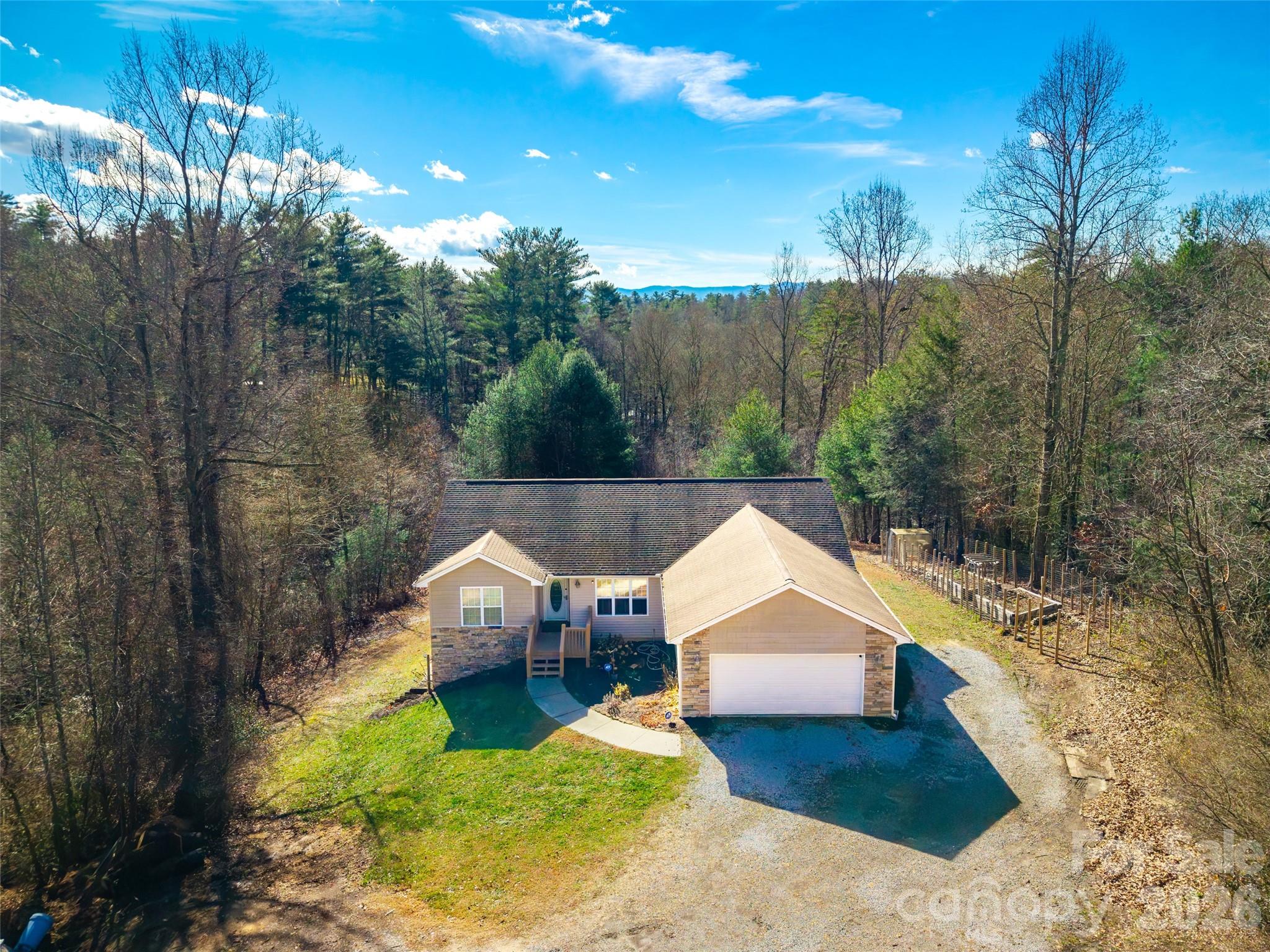 If you've been searching for a home with acreage in Hendersonville, NC, this one checks the boxes. Set at the end of a quiet gravel road on 3.61 usable acres in Henderson County, 151 Willard Lane delivers the privacy, space, and flexibility that's hard to find this close to town — no HOA, no restrictions, and room to actually do something with the land.

This 3-bedroom, 2-bath home in the Blue Ridge foothills is a natural fit for small business owners, contractors, tradespeople, and homesteaders — anyone who needs space for trucks, trailers, heavy equipment, boats, or outdoor projects. Whether you're running a business from home, building a hobby farm, or just want elbow room, the open, level acreage is ready to work.

Inside, soaring living room ceilings flow into a dining area and functional galley kitchen — comfortable for everyday living and easy for entertaining. The primary suite features a custom walk-in closet with built-ins and an updated bath with a brand-new glass shower door. A partially finished basement gives you immediate flex space — think home office, workshop, gym, guest suite, or rec room — with the bones already in place.

Step outside to a new back deck overlooking the property, complete with raised garden beds and plenty of room to expand. The attached two-car garage adds covered storage and all-weather parking, and with 3.61 acres, there's a natural second building site — perfect for multigenerational living, a detached shop or studio, or future expansion.

Location-wise, you're dialed in. Easy access to the Blue Ridge Parkway, Pisgah National Forest, hiking, fly fishing, and waterfall trails — all the outdoor recreation that draws people to Western North Carolina. Downtown Hendersonville's restaurants, breweries, and shops are just minutes away. Asheville is a quick drive up the road.
This is the Western NC acreage property buyers keep searching for — private, flexible, and priced to move. Bring your tools, your trucks, and your vision.