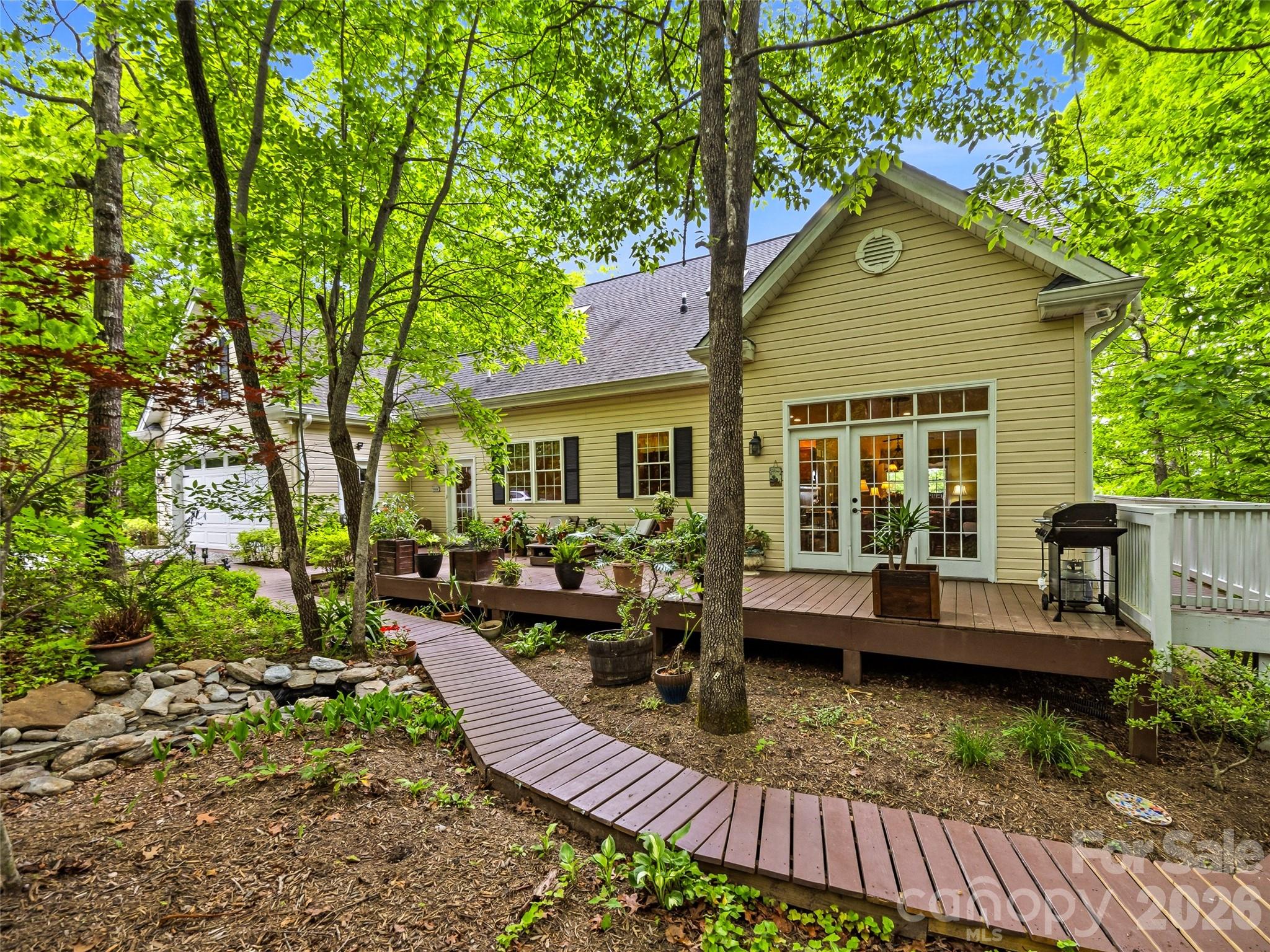 Nestled in a woodland wonderland with beautiful mountain views, this custom-built home offers the perfect blend of comfort, craftsmanship, and tranquility. Relax on the wraparound covered porch and enjoy cool mountain breezes from your favorite rocking chair. Designed for convenient main-level living, the home features a spacious primary suite with a tiled walk-in shower, an open-concept living, dining, and kitchen area ideal for gathering, a half bath, and an attached two-car garage. With three separate HVAC systems, comfort is easily maintained throughout the home's generous living spaces. Upstairs, you'll find two spacious bedrooms and a full bath, while the lower level offers additional bonus rooms, a full bath, den, laundry area, and flexible space to accommodate guests, hobbies, or multi-generational living. High, smooth-finished ceilings and a dramatic two-story atrium foyer create an inviting sense of openness, while the upper landing frames a picturesque mountain view. The outdoor setting is equally impressive, with wooden walkways meandering through mature daylilies, perennial gardens, and natural landscaping. A bubbling water feature adds a peaceful ambiance to this private mountain retreat.

The detached garage includes an additional upper-level storage area accessed by a spiral staircase, providing ample room for seasonal items and equipment.

Lovingly built and meticulously maintained by the owner-builder from the very first shovel of dirt, this exceptional property reflects pride of ownership throughout. Priced below a recent appraisal, this is a rare opportunity to own a thoughtfully crafted mountain home in a truly special setting.