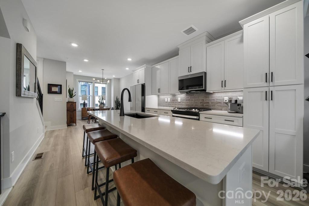 Perfectly positioned in the heart of South End, this stunning four-story townhome places Charlotte's best restaurants, breweries, coffee shops, boutique shopping, and the LYNX Blue Line just steps from your front door—making it easy to leave the car behind and embrace one of the city's most walkable neighborhoods.
Inside, contemporary design meets effortless luxury. Sunlight pours through oversized windows, highlighting the open-concept floor plan, designer finishes, and luxury vinyl plank flooring throughout. The gourmet kitchen is truly the heart of the home, featuring a large entertaining island, gas range, premium appliances, and stylish finishes that seamlessly flow into the living and dining spaces—perfect for hosting friends or enjoying a quiet evening at home. The spacious primary suite provides a true retreat with a spa inspired bath, dual vanities, and a beautifully tiled walk-in shower. Upstairs, the versatile loft offers endless possibilities as a home office, media room, fitness space, or guest lounge before opening to one of the home's most impressive features a private rooftop terrace. Whether you're enjoying your morning coffee, entertaining under the stars, or simply taking in the energy of the city, this is a space you'll find yourself using year round. A tandem two-car garage with upgraded epoxy flooring completes the home with both convenience and functionality.