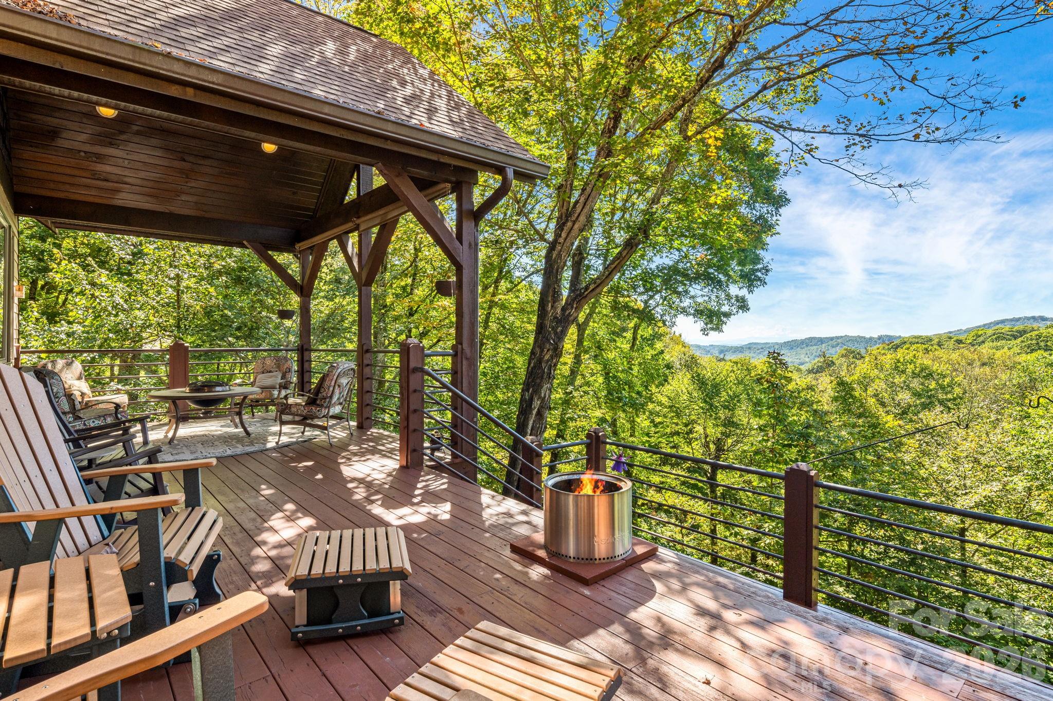 Perched at 4,100 feet inside Wolf Laurel’s 5,300 acre gated mountain community, 191 Ivy Way delivers the rare WNC combination buyers ask for again and again, year round, long range mountain views and flowing creeks across the property. Backing up to the Pisgah National Forest and set on six contiguous lots totaling 3.4 acres, this private retreat is surrounded by native rhododendron, hardwoods, wildflowers, and the peaceful sound of water below.
The four bedroom home is designed for comfortable year round living, with a welcoming foyer opening into a vaulted great room anchored by a dramatic floor-to-ceiling stone fireplace. Large windows frame layered Blue Ridge views, while the dining area and gourmet island kitchen offer granite countertops, gas range, generous storage, and easy gathering space. The main level includes the primary suite, media room, half bath, office, laundry, and expansive covered decks that live like outdoor rooms.
Upstairs are two additional bedrooms and a full bath, including a bedroom with private balcony overlooking the mountains and creeks. Wraparound decking offers sunny and shaded spaces for morning coffee, evening fire-pit gatherings, and quiet moments in the trees. The oversized two bay garage features higher clearance doors for larger vehicles, plus room for a workshop or game area, complete with a wood stove for winter months. One bedroom with ensuite full bath and bonus room provide flexible overflow guest space. Furnishings convey for an easy turnkey handoff.
Equity Village Club Membership conveys, offering access to the pool, pickleball, tennis, sports courts, playground, pavilion, stocked trout pond, and event center. Optional Wolf Laurel Country Club membership adds the beautiful 5 star golf course, dining, bar, 24 hr fitness center, and club amenities. Enjoy 50 miles of internal hiking trails, multiple Appalachian Trail access points, Hatley Pointe skiing, Smoke & Timber dining, and the magic of a true high-elevation mountain lifestyle.
