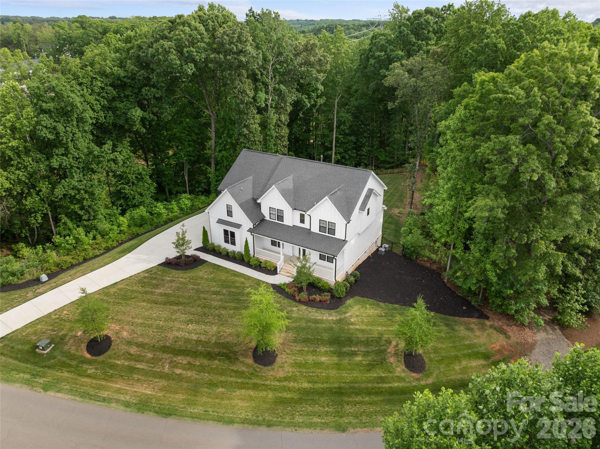 Tucked into the rolling topography of Anniston, one of Davidson’s most coveted communities, this custom modern farmhouse delivers high-end design with a warm, down-to-earth heart.

Perfectly positioned on a premium 1.3-acre lot, this home offers a rare degree of privacy. Because the property backs directly to mature woods and protected common area, you enjoy massive separation from neighbors on both sides, a buffer that simply cannot be replicated.

A classic rocking-chair front porch welcomes you into a light-filled floor plan that effortlessly balances everyday comfort with elevated finishes. Hardwood floors run throughout the main level living areas, grounding the open-concept layout in warmth and texture.

The gourmet kitchen is a true chef’s dream, featuring a bespoke range hood, gas cooktop, double ovens, an oversized island built for gathering, and an expansive layout that flows seamlessly into the main living areas. Tucked just off the kitchen, a true butler’s pantry provides the ultimate hidden workspace for meal prep and entertaining, the kind of detail that separates a good home from a great one.

The adjacent dining room boasts a deep coffered ceiling, adding architectural elegance to every dinner party. The living room anchors the heart of the home with a stunning gas fireplace and a massive picture window, giving you front-row seating to watch the foliage unveil itself in the surrounding woods each autumn.

The main level is exceptionally functional, featuring a private downstairs guest suite with a full bathroom and an attached flexible room perfectly sized for a home office, nursery, or playroom, ideal for multi-generational living or work-from-home households.

Upstairs, the luxury primary retreat lives as a private wing, complete with brand-new high-end carpet, a fully organized custom closet system, and a spa-like bathroom showcasing a free-standing soaking tub, a beautifully tiled walk-in shower, and double vanities.

Three additional secondary bedrooms reside on this level. Two boast striking cathedral ceilings, with one featuring a private en-suite bath and the remaining two sharing a smart Jack-and-Jill layout, the kind of thoughtful design that makes daily life with family genuinely easier.

A massive upstairs bonus room serves as the ultimate media or recreation hub, located just steps from an oversized laundry room packed with built-in cabinetry for seamless storage.

The rear of the property is built for relaxed outdoor living, centered around a large covered back deck overlooking your expansive, tree-lined backyard, the kind of space made for slow morning coffees, long dinners with friends, and unhurried evenings under the stars.

Complete with a 3-car garage, this home delivers a massive financial “wow factor”: because it sits just outside the Davidson town boundaries, buyers bypass city tax rates and pay only low Iredell County property taxes, a meaningful savings that compounds year after year.

Homes like this, on lots like this, in communities like this, do not come available often. Come walk the property, stand on the back deck, and feel why Anniston has become one of the most quietly sought-after addresses in the Lake Norman area. Your next chapter is waiting.