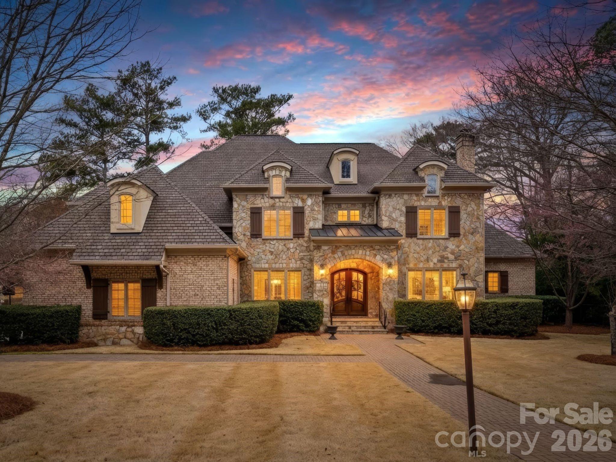 Welcome to 2224 Carmel Rd-a stately brick and stone home built in 2007, offering over 5,000 square feet of well-designed, flexible living spaces ideal for both everyday comfort and easy entertaining. The convenient oversized primary suite on the main level features a sunny sitting area or office space, a spa-like bath with heated tile floors, and two custom walk-in closets. The open floor plan connects the kitchen and breakfast area to a comfortable family room with custom built-ins, while the grand entry foyer is flanked by formal living and dining rooms. The recently refreshed kitchen with new backsplash and painted cabinets features two sinks, double ovens, a six-burner range, and tons of prep and storage space. A spacious laundry room with sink and mudroom create a functional drop zone adjacent to a large three-car garage. Upstairs, three additional bedrooms with tall ceilings each offer attached baths. A giant recreation room includes a wet bar, refrigerator, and dishwasher drawer, along with custom built-ins. Additionally, there is another bonus space perfect as a 5th bedroom, home gym, or office space. Large walk-in attic space provides easy access storage. Situated on a private .81-acre lot, this fully gated property offers a circular drive and two electronic gates for added security and presence. Low-maintenance Zoysia grass and an in-ground irrigation system enhance the beautifully maintained grounds. The backyard is a true retreat, complete with a screened porch featuring a wood-burning fireplace, patio, fire pit, and a heated saltwater pool with full fencing—creating a wonderful outdoor living experience with total privacy.