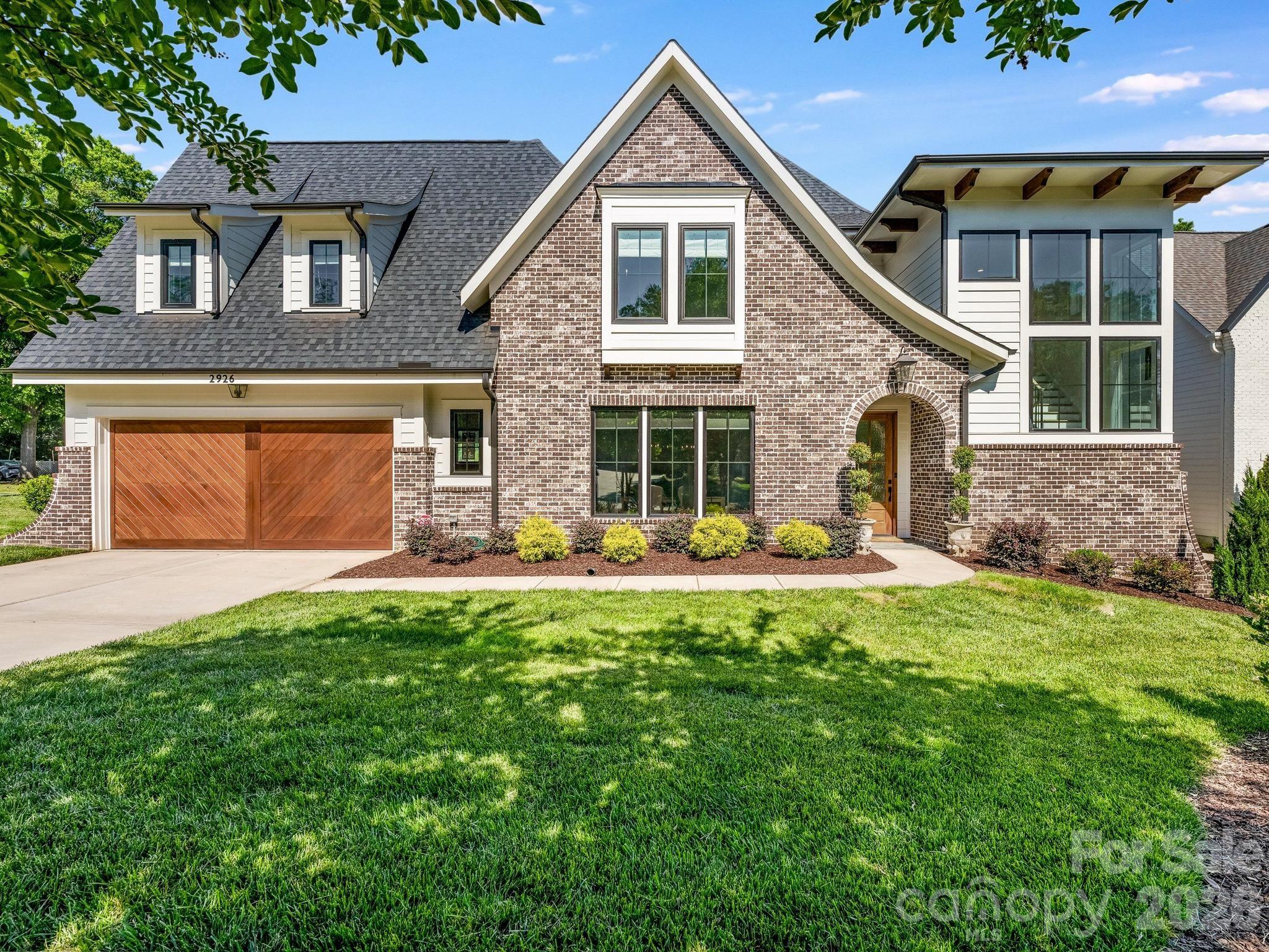 Built by Alenky Signature Homes in 2024 and located in Charlotte’s highly sought-after Sedgefield neighborhood, this refined luxury duet lives like a single-family home with thoughtfully designed spaces for both entertaining and everyday living, including a rare main-level primary suite. Upon entry, expansive living spaces, soaring ceilings, and a striking statement stairwell framed by dramatic floor-to-ceiling windows create a light-filled, airy feel throughout the main level. The chef’s kitchen features professional-grade JennAir appliances, custom cabinetry, quartz countertops, abundant storage, and an oversized island anchoring the open-concept living and dining areas. A built-in bar with glass-front cabinetry and a beverage refrigerator adds style and function for entertaining. The living room is centered around a beautiful fireplace with custom surround, while large folding doors open to a covered porch with a second fireplace and bluestone flooring. The vaulted main-level primary suite offers a private retreat with a spa-inspired bath featuring dual vanities, a soaking tub, an oversized frameless glass curbless shower, and an expansive walk-in closet. Upstairs includes three spacious bedrooms, two full baths, a large den, and multiple walk-in attic spaces providing exceptional storage. Additional highlights include custom window treatments, an irrigation system, EV charger, and a two-car garage. Ideally situated just moments from Uptown Charlotte, Dilworth, Myers Park, and South End, this home offers convenient access to some of Charlotte’s best dining, shopping, parks, and entertainment.