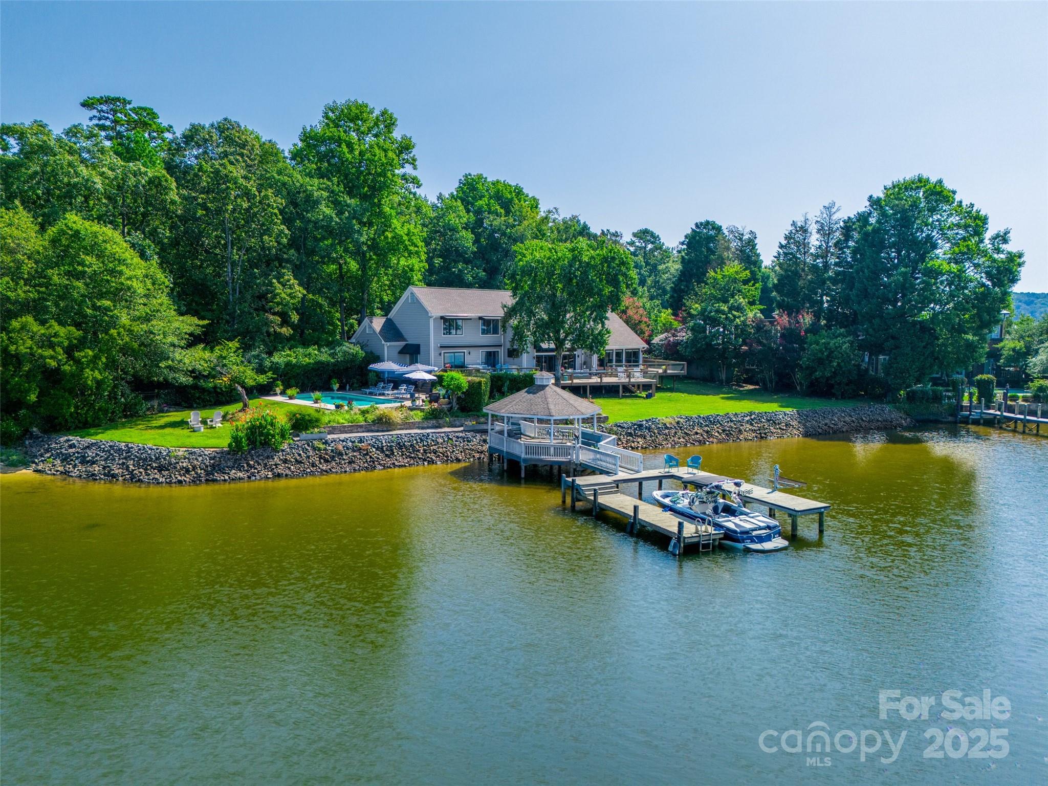 Welcome to a rare offering of unparalleled beauty and sophistication—a lakefront estate boasting 250 feet of pristine shoreline and sweeping, panoramic water views. Nestled in an exclusive gated community.Expansive windows and thoughtfully designed living spaces capture the ever-changing light over the water, offering breathtaking vistas from nearly every room. Step inside to discover soaring ceilings, rich hardwood floors, and bespoke finishes throughout. The heart of the home is a grand living area that opens seamlessly to the outdoors, perfect for both intimate gatherings and large-scale entertaining. A chef’s kitchen, formal dining room, and multiple lounge spaces provide refined comfort and effortless flow.The primary suite is a private sanctuary with stunning lake views.
Don't miss a sunset from the swimming pool and hot tub. Fully fenced lot.
This is more than a home—it’s an estate that offers peace, privacy, and prestige on one of the most coveted stretches of shoreline.