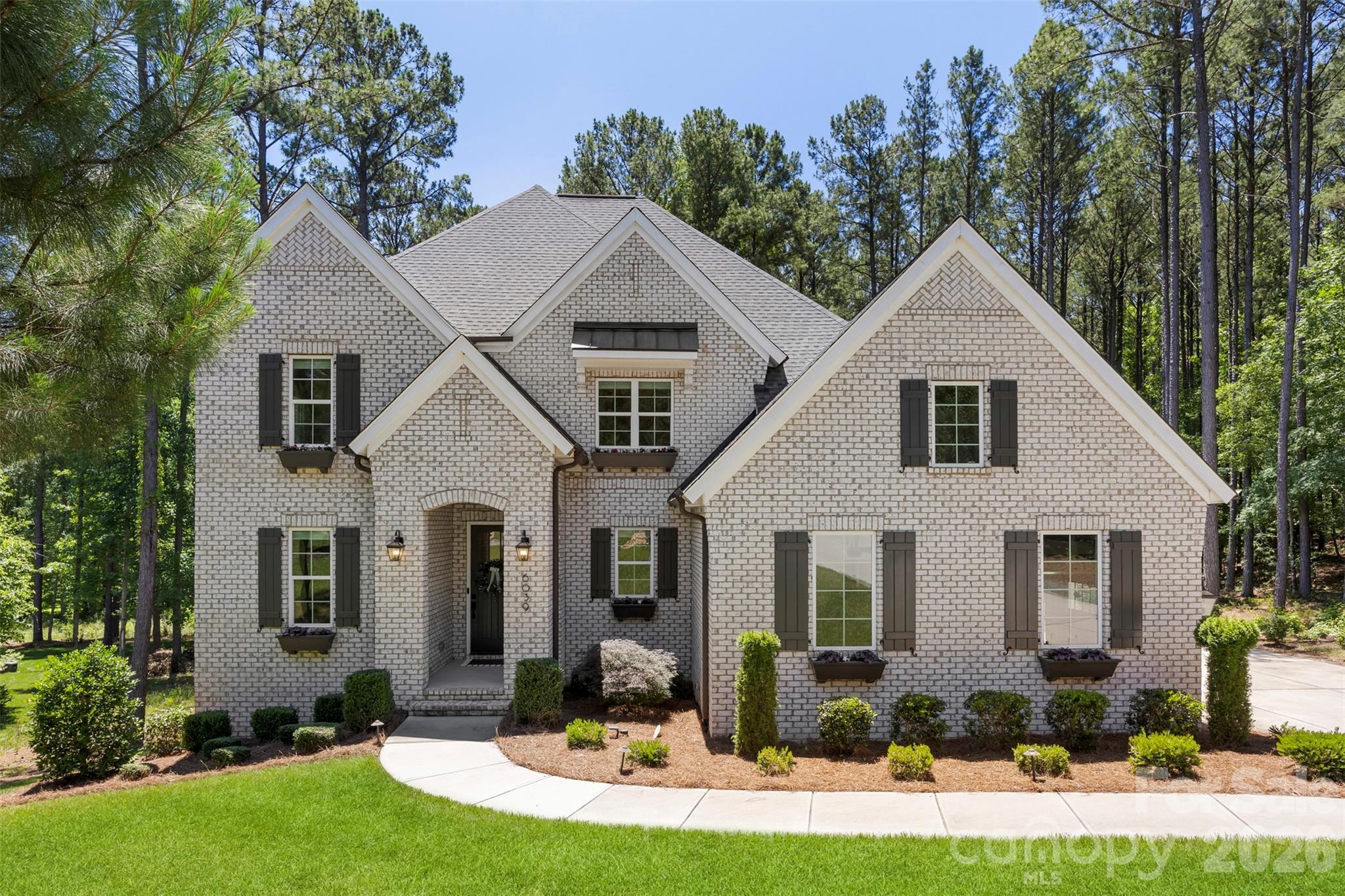 Set on a private 1.26-acre wooded lot in Riverchase Estates, this 5-bedroom, 4.5-bath home blends luxury with everyday comfort and true indoor-outdoor living just 20 minutes from Indian Land shopping and dining. The main level features a spacious primary suite, dedicated study with custom built-in desk, an additional flex space, and a stunning living area with fireplace that flows into an all-season room and covered porches. The gourmet kitchen is a standout, complete with a Wolf dual fuel range, Sub-Zero built-in refrigerator, and KitchenAid appliances. Downstairs, the finished walk-out basement equipped for a second kitchen is designed for entertaining with a home theater and surround sound throughout. Additional highlights include custom closet in the owners suite, a side-entry 3-car garage, tankless water heater, Nest thermostat, and a custom firepit area at the back patio. A transferable 10-year structural warranty provides added peace of mind until 2032.  Residents enjoy access to resort-style amenities including the Eagles’ Common Clubhouse, pool, fitness center, sports courts, scenic trails, access to the Catawba River and a 500-acre nature preserve making this home the perfect balance of privacy, space, and community living.