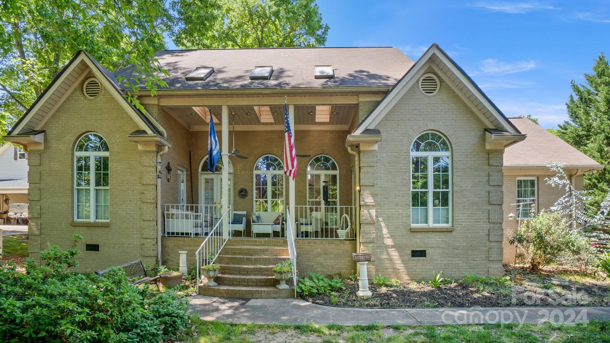 Immerse yourself in the beauty of views of the lake from the inviting front porch of this tranquil brick ranch home. Cathedral ceilings lend an airy feel to the spacious interior, complemented by gleaming hardwood floors, refined formal dining area, and cozy family room centered around a gas fireplace with a TV niche. The upgraded kitchen features Quartz counters and a convenient desk niche. Parking is a breeze with an oversized 1 car garage, detached 2 car garage/workshop (w/plumbing & HVAC), and a large carport perfect for accommodating an RV or multiple vehicles. Retreat to the expansive master suite featuring a luxurious bath and a generous walk-in closet, offering the ultimate in relaxation and comfort. Located in a prime area, this home offers both convenience and serenity, making it an ideal waterfront haven. Garage has bathroom and HVAC NEW House HVAC just installed, and new roof soon.   Be sure to check out the 2 additional parcels on the lake with gazebo and dock!
