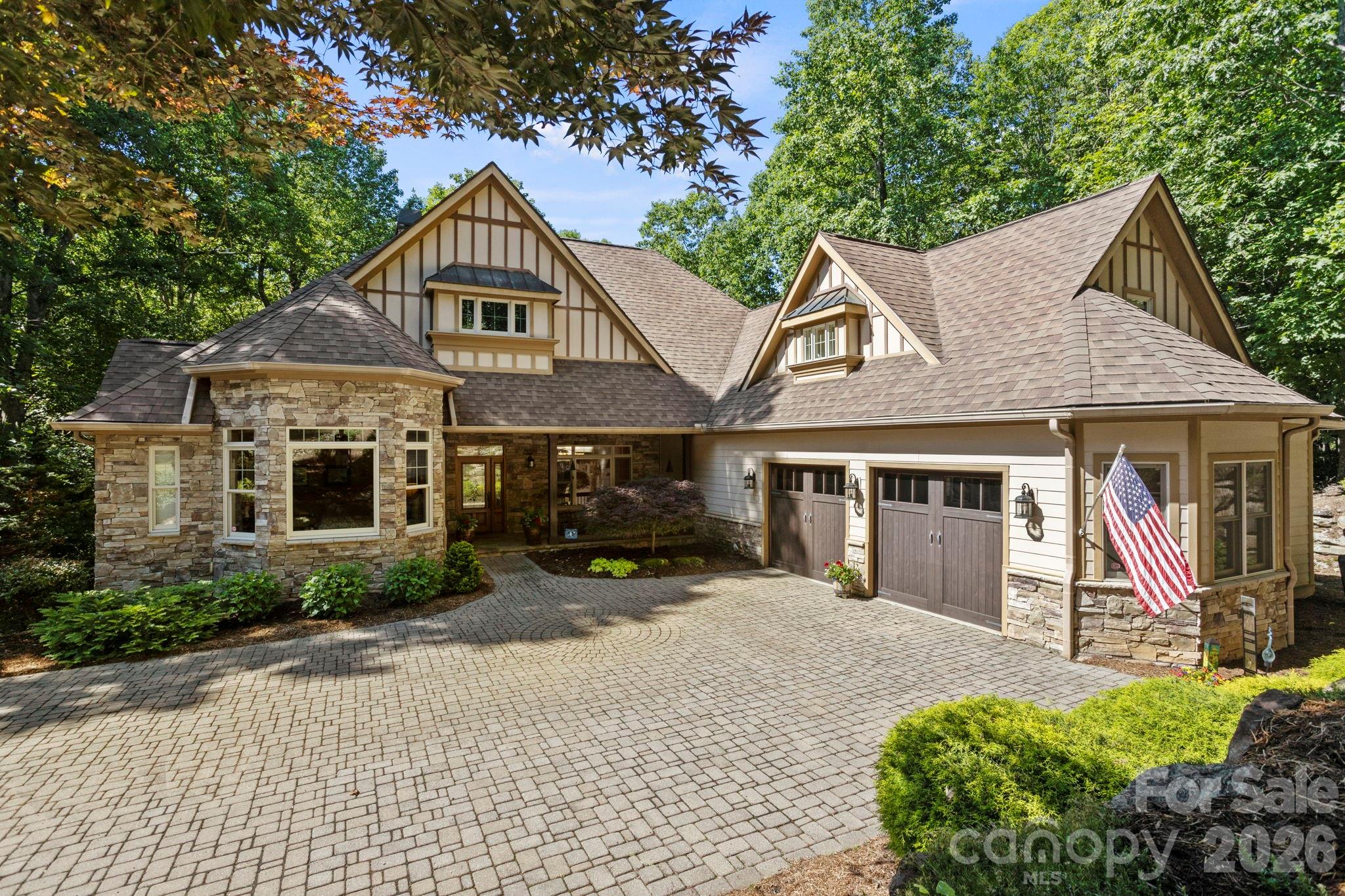 Experience the pinnacle of luxury mountain living in this exceptional custom high-end home gracefully situated on 1.46 acres of exquisitely landscaped, park-like grounds in prestigious Kenmure - a highly desirable gated golf course community. Prepare to be impressed as you travel the elegant paver driveway with expansive guest parking surrounded by spectacular stonework, boulder accents and impressive rock retaining walls. Built by one of Western North Carolina’s premier luxury home builders, this architectural masterpiece welcomes you through a covered slate front porch into an extraordinary home showcasing soaring ceilings, exceptional architectural details, rich hardwood flooring and an inviting open floor plan designed for effortless entertaining. The magnificent great room is the centerpiece of the home featuring a dramatic floor-to-ceiling stone fireplace flanked by custom built-ins, coffered vaulted ceilings and a wall of windows with doors leading to the spectacular covered deck. This remarkable outdoor living space features a stunning floor-to-ceiling stone fireplace and overlooks the most breathtaking private natural setting imaginable. The professionally designed gourmet kitchen is a chef’s dream appointed with beautiful granite countertops, tile backsplash, premium stainless steel appliances, abundant custom cabinetry, pantry and exceptional workspace. The kitchen flows seamlessly into the breakfast room and elegant dining room with coffered ceiling and walls of windows creating the perfect setting for entertaining family and friends. The luxurious main-level primary suite is a private retreat featuring a tray ceiling, bay window sitting area, 2 spacious walk-in closets, additional linen closet and an incredible spa-inspired bath with heated tile floors, whirlpool tub, oversized walk-in tiled shower, granite double vanities and designer finishes. Two additional main-level guest suites each offer beautifully appointed private baths and walk-in closets. Completing the main level is an elegant powder room with vessel sink, an oversized laundry room featuring granite countertops, abundant cabinetry, utility sink and a unique custom staircase accented with custom bookshelves and an office nook leading to the lower level. The upper level offers a spacious bonus room with a full bath providing endless possibilities for a home office, fitness room, studio or additional guest accommodations. Designed for exceptional entertaining the spectacular lower level showcases a custom staircase leading to a state-of-the-art theater room complete with equipment and theater seating. The theater flows seamlessly into the expansive family room featuring another floor-to-ceiling stone fireplace, walls of windows, billiards area and an incredible full-service bar with granite countertops, sink, wine cooler and custom cabinetry. This level also features a second luxurious primary suite with sitting area, spa-quality bath offering a walk-in tiled shower, granite double vanity and walk-in closet, an additional full bath, flexible bonus space, abundant storage and a convenient secondary staircase providing direct access to the garage. Outdoor living is simply extraordinary. Relax on the covered slate front porch, unwind beside the magnificent covered deck fireplace or enjoy the expansive lower-level deck and outdoor living areas surrounded by lush landscaping, mature plantings, extensive hardscaping, natural stonework and tranquil wooded privacy that creates a true park-like sanctuary. Additional luxury amenities include a two-car plus golf cart garage w/ epoxy flooring, generator, Hunter Douglas window treatments, tankless water heater, updated premium kitchen appliances, newer designer lighting and ceiling fans, multi-zone irrigation system and countless high-end upgrades throughout. This remarkable estate represents the very finest in luxury mountain living offering uncompromising quality, exceptional privacy and an extraordinary lifestyle!
