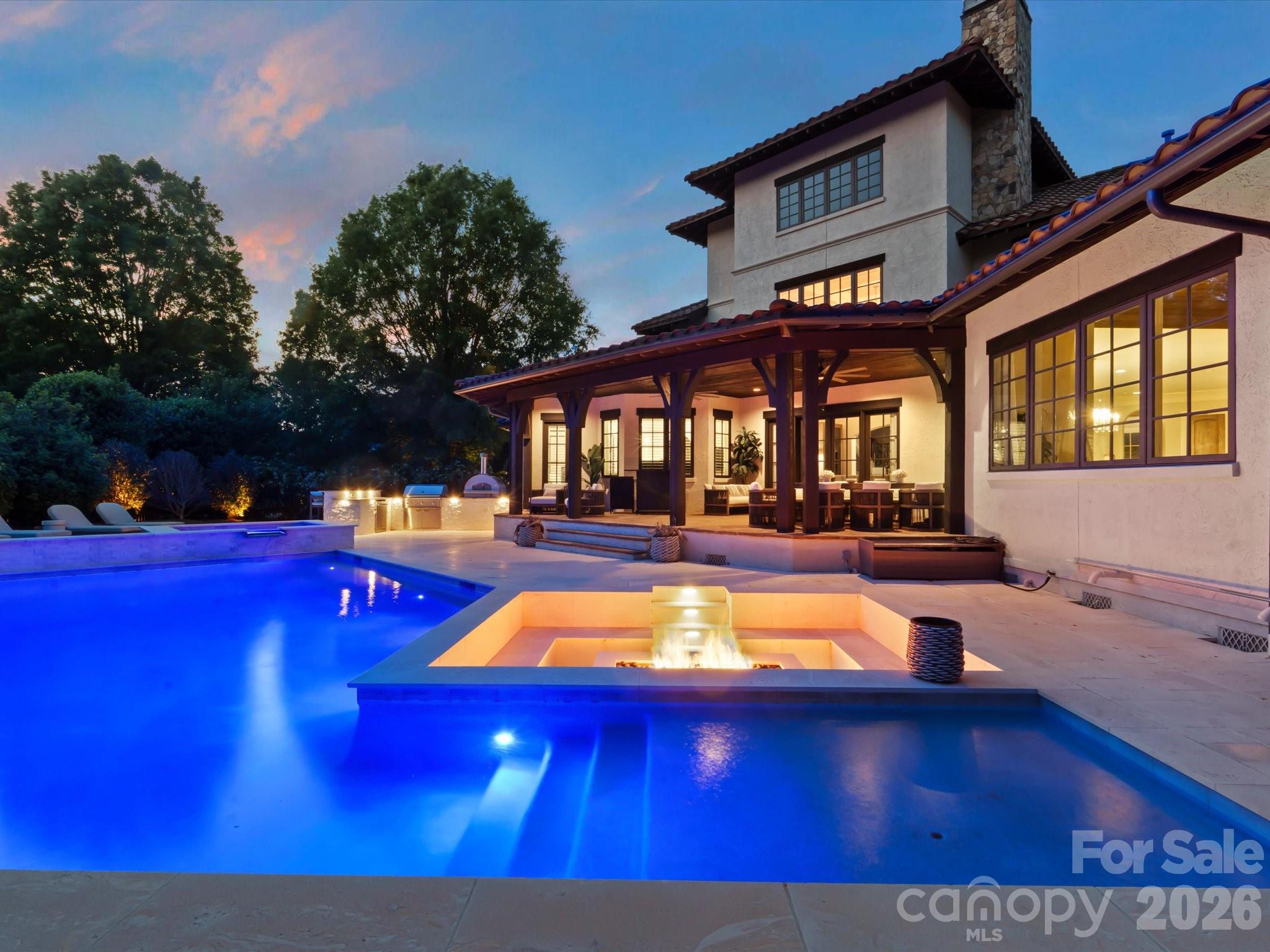 Situated within the prestigious guard-gated community of Longview, this exceptional luxury residence offers a rare combination of privacy, sophistication, and resort-style living in one of the Charlotte area’s most exclusive neighborhoods. Designed for both everyday comfort and elevated entertaining, the home features a well-proportioned layout with a luxurious primary suite on the main level, offering direct access to the expansive patio and stunning saltwater pool. From quiet mornings by the water to evenings entertaining guests under the Carolina sky, the outdoor living experience is truly exceptional. The backyard was designed to rival a private resort, featuring an extraordinary pool and spa project with integrated fire features and extensive hardscaping representing nearly half a million dollars in improvements. Outdoor living is elevated even further with a fully equipped kitchen featuring a new grill, pizza oven, refrigerator, and a smart-controlled fire pit that creates the perfect atmosphere year-round. Low-maintenance artificial turf adds both beauty and convenience to the outdoor space. Inside, the home blends timeless architecture with refined modern updates. Recent improvements include a new refrigerator, new double ovens and range, updated designer chandeliers throughout the entry, kitchen, breakfast area, and den, plantation shutters throughout the home and garage, custom draperies, and designer wallpaper accents in the powder room and third-floor bonus room. Beyond the home itself, Longview delivers a lifestyle few communities in the region can match. Known for its full-time guarded entrance, exclusivity, and exceptional amenities, residents enjoy a private country club atmosphere with beautifully maintained surroundings, golf, tennis, fitness, dining, and social events, all while remaining conveniently located near Charlotte.