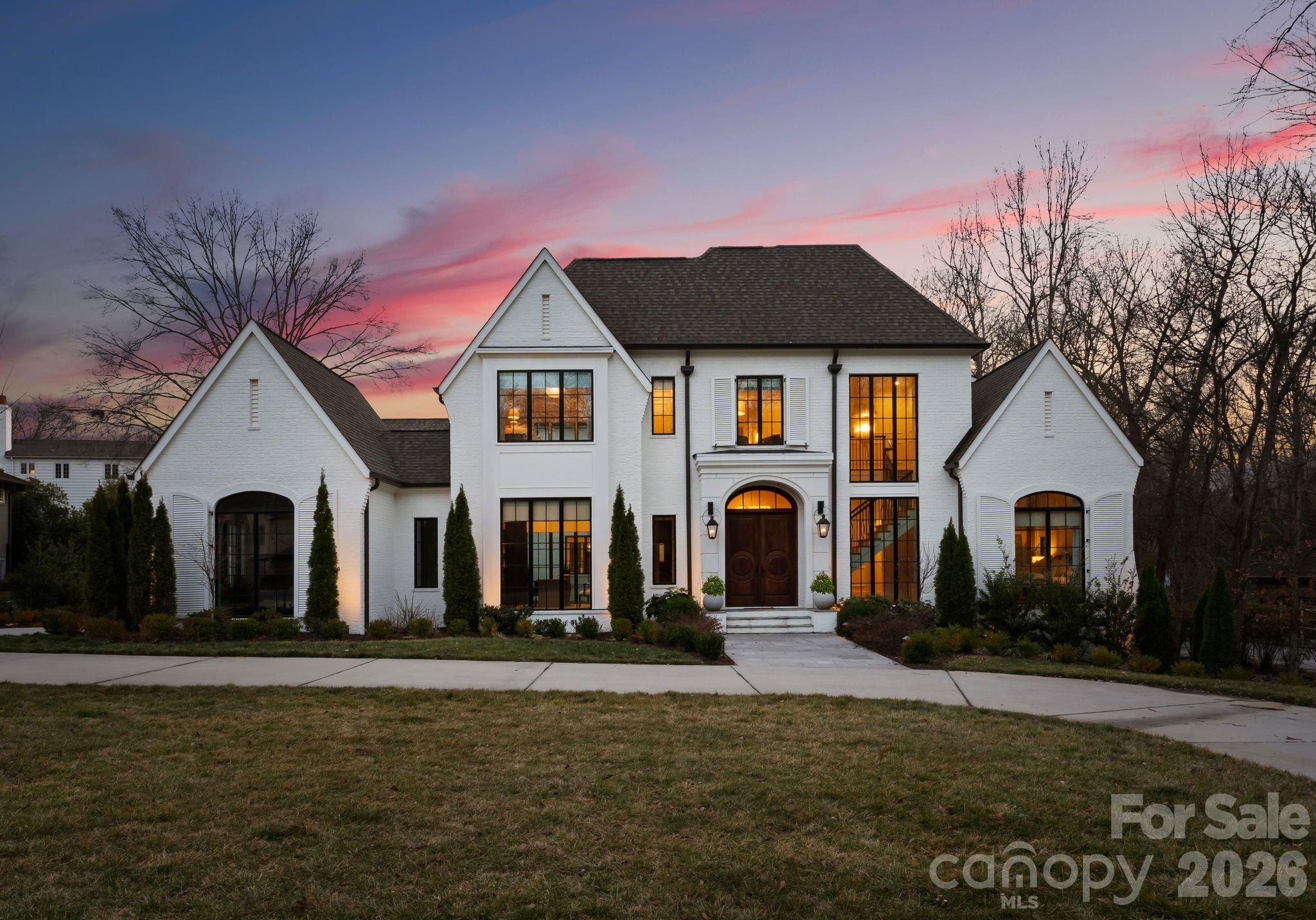 Just listed in the prestigious Carmel Country Club, this extraordinary modern European estate offers over 6,600 square feet of refined design and resort-inspired living. A striking white brick façade and arched front entry make an unforgettable first impression, while inside, warm hardwoods, exposed beams, designer lighting, and curated finishes create a home that feels both sophisticated and inviting. The chef’s kitchen is a true centerpiece, featuring an oversized walnut island, marble backsplash, professional-grade appliances, and a fully appointed scullery—perfect for effortless entertaining. The open-concept living spaces flow seamlessly to a covered porch overlooking the backyard oasis. The main level includes a luxurious primary suite with a spa-inspired bath and expansive custom closet, a private office, formal dining room, and an additional guest bedroom—offering flexibility for multi-generational living. Upstairs, four spacious bedrooms, a large bonus room, exercise room, laundry, and generous storage provide exceptional functionality for today’s lifestyle. Step outside to a resort-caliber setting complete with a heated pool and spa, expansive paver terrace, fire feature, and a beautifully flat backyard with room to play. Designed for both grand entertaining and intimate evenings under the stars, this outdoor living space rivals the finest retreats. Located in one of Charlotte’s most coveted country club communities, this home seamlessly blends timeless architecture, modern luxury, and everyday livability.