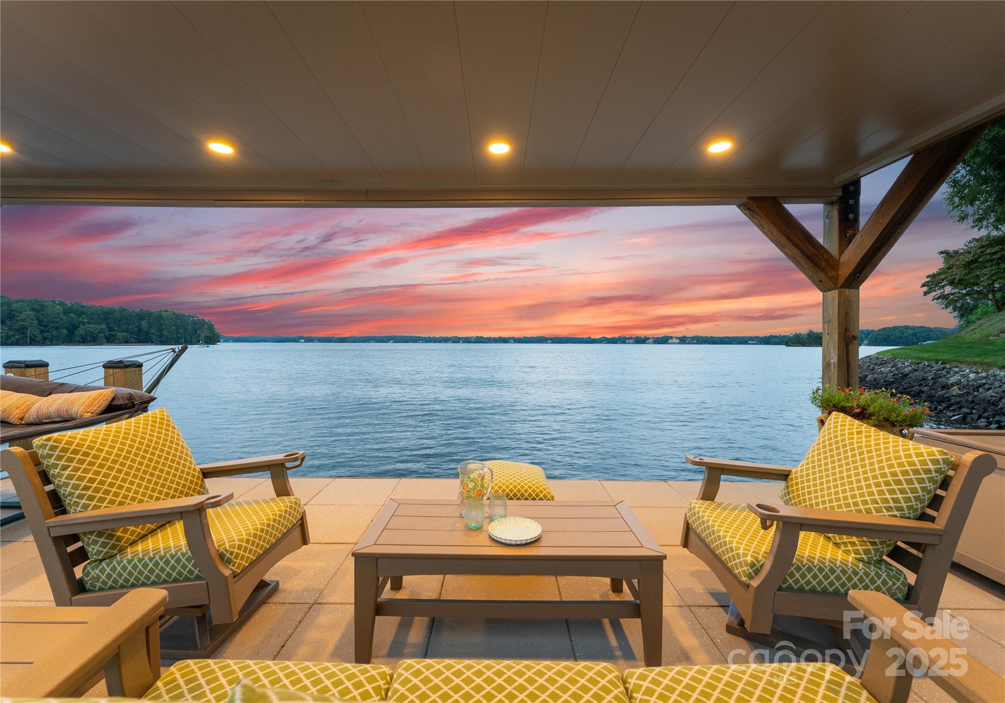 Custom Lake Norman home on Brawley School Rd Peninsula, boasting approximately 475 ft of unmatched main channel waterfront views w/ stunning sunrise vistas. Features a Lancaster double-decker dock w/ retractable boat cover on deep water, near Trump National & LKN Yacht Club. This 4-bedroom, 4.5 Bathroom home includes a main-level primary suite w/ an octagonal tray ceiling & large vaulted sitting room w/ panoramic views. The primary bath features custom cabinets, quartz counters, & stylish hardware. The kitchen showcases custom inset cabinets, a farmhouse sink, Viaterra Minuet Quartz counters w/ 3" mitered edge island, stylish hood, Six burner commercial Wolf range, Wolf Steam oven, 2-Miele Dishwashers & Subzero fridge. Highlights include a foyer w/ wainscoting, tongue & groove vaulted ceiling in the great room w/ a custom barnwood fireplace mantel, Cambria Quartz in baths & laundry room, family room on lower level w/ ample storage including a lower-level shop and an outdoor shower