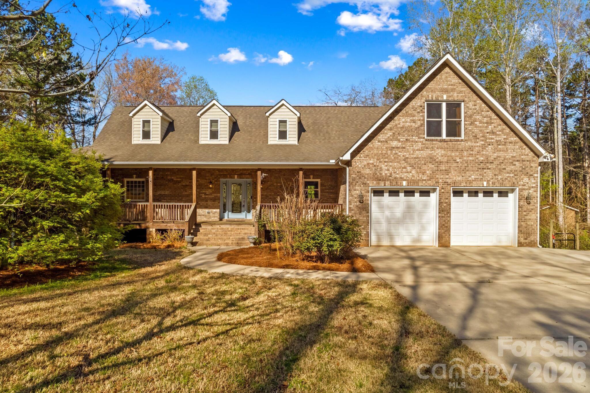 Beautiful custom-built brick home located in Wood Duck Cove at High Rock Lake, offering over 4,000 square feet of thoughtfully designed living space with room for everyone. The main level features a desirable split floor plan with a spacious primary suite complete with a tile shower and jetted tub, along with a stunning living room showcasing vaulted ceilings and a stone fireplace overlooking the private, peaceful backyard. The kitchen is equipped with stainless steel appliances and opens seamlessly to the dining area, perfect for everyday living and entertaining. Two additional bedrooms, a full bath, and a laundry room complete the main level. Upstairs, you’ll find another full bathroom, two flexible spaces, and a bonus room over the garage. The basement provides incredible versatility with a bedroom, full bath, additional flex space, plus unfinished storage and workshop areas. Two lots with 1.49 acres, the property offers exceptional storage and parking options including a 2-car attached garage, detached garage, and basement garage—ideal for boats and recreational equipment. Enjoy peaceful outdoor living from the charming wraparound porch, with convenient access to lake amenities including a community boat ramp and dock just moments away. Ideally located with easy access to I-85, this exceptional home offers the perfect balance of luxury, privacy, and convenience.