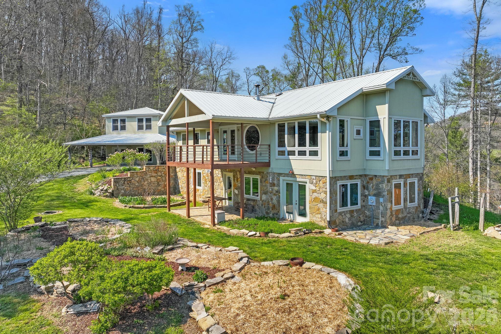 Stunning custom home and guest cottage on 31 MOL private acres at the end of a private gated driveway just a short drive to Downtown Marshall off Little Pine Road.  Main house has an additional bonus room w/closet and features an open floor plan with many windows and long range mountain views from almost every room in the house. Built in wood burning fireplace with tile surround and wood stove as well as a zoned HVAC system.  Custom stained glass windows throughout and beautiful hand painted malalacite treated concrete floors on lower level.  The adjacent guest cottage conveys with all the furnishings and has radiant floor heating.  The lower level guest cottage is stubbed for kitchen and bathroom but currently unfinished and makes a perfect studio or sunroom.  Dreamy homestead setting w/established perennial flowers, strawberry, rhubard and asparagus beds and mature blueberry and hybrid cherry bushes as well as a trail down to a bounding creek.