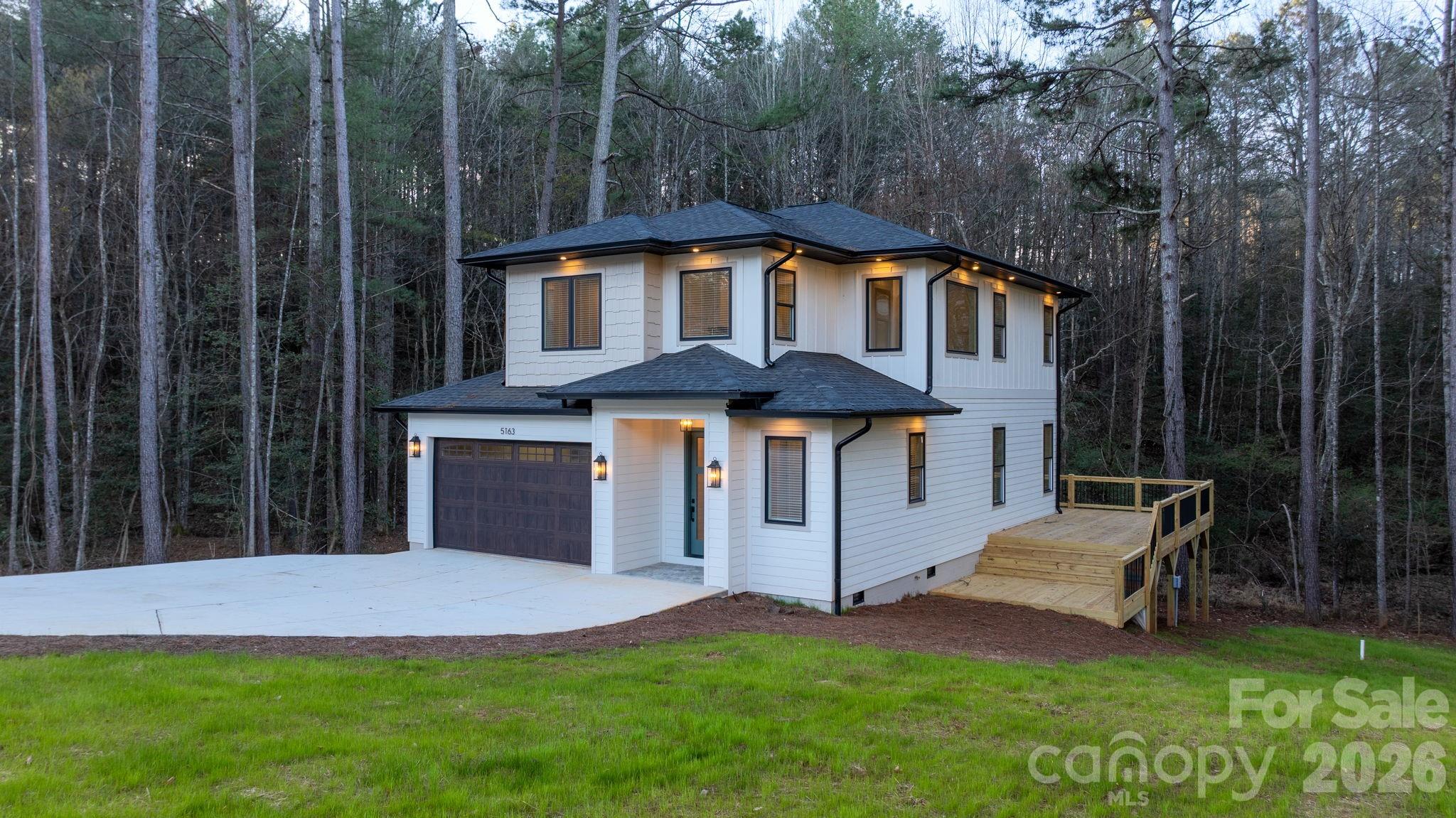 Motivated Seller!! Welcome to this beautifully crafted modern home located near Lake Hickory, offering a serene wooded backdrop and seasonal lake views that enhance the setting. Thoughtfully designed with comfort, style, and functionality in mind, this 2-bedroom, 2.5-bath residence features an impressive layout with elevated finishes throughout.
The main level opens into a bright and inviting living space where large windows frame the natural surroundings and allow sunlight to fill the room. Rich hardwood flooring runs throughout the entire home, setting the tone for the home’s warm yet modern aesthetic. The living room flows effortlessly into the dining area and kitchen, creating an ideal open-concept environment for both everyday living and entertaining.
The kitchen is a standout feature, designed with custom cabinetry, quartz countertops, stainless steel appliances, and two kitchen sinks for added convenience and functionality. Ample counter space and thoughtful storage provide both beauty and practicality, making this a kitchen that truly supports cooking, hosting, and daily routines.  The small office or storage space and half bath on the main level adds ease for guests and the adorable pet area under the stairs for the furry family members completes the main living area.
Upstairs, the thoughtful design continues with a spacious primary suite offering comfort and privacy. The primary bedroom includes generous space, a large walk in closet with custom shelving and storage and the adjoining bathroom features quality tilework and tasteful finishes. The secondary bedroom is also well-sized and located near the second full bath that also includes beautiful tile work and thoughtful finishes.
The upper level also includes multiple flex rooms, providing the opportunity to customize the home to your needs—whether you envision a home office, creative studio, exercise room, media area, or an additional lounge space. These versatile rooms add significant function and value to the home while maintaining the same elegant style found throughout.
Additional highlights are the attached 2 car garage and a concreted area in crawlspace for storage and the large laundry room with easy access upstairs with counter space, utility sink and more custom cabinets. The oversized deck spans the back of the home, offering an inviting outdoor extension of the living space. This is perfect for entertaining, dining or just relaxing with the natural settings to enjoy.