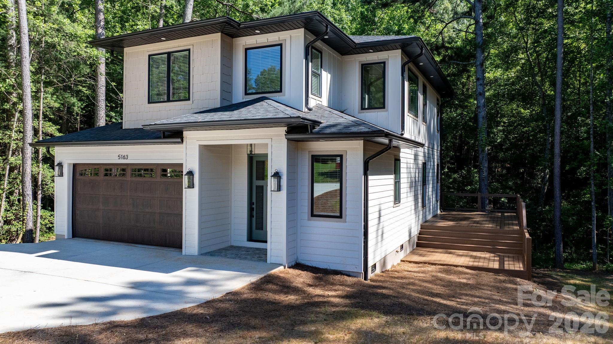 Motivated Seller!! Welcome to this beautifully crafted modern home located near Lake Hickory, offering a serene wooded backdrop and seasonal lake views that enhance the setting. Thoughtfully designed with comfort, style, and functionality in mind, this 2-bedroom, 2.5-bath residence features an impressive layout with elevated finishes throughout.
The main level opens into a bright and inviting living space where large windows frame the natural surroundings and allow sunlight to fill the room. Rich hardwood flooring runs throughout the entire home, setting the tone for the home’s warm yet modern aesthetic. The living room flows effortlessly into the dining area and kitchen, creating an ideal open-concept environment for both everyday living and entertaining.
The kitchen is a standout feature, designed with custom cabinetry, quartz countertops, stainless steel appliances, and two kitchen sinks for added convenience and functionality. Ample counter space and thoughtful storage provide both beauty and practicality, making this a kitchen that truly supports cooking, hosting, and daily routines.  The small office or storage space and half bath on the main level adds ease for guests and the adorable pet area under the stairs for the furry family members completes the main living area.
Upstairs, the thoughtful design continues with a spacious primary suite offering comfort and privacy. The primary bedroom includes generous space, a large walk in closet with custom shelving and storage and the adjoining bathroom features quality tilework and tasteful finishes. The secondary bedroom is also well-sized and located near the second full bath that also includes beautiful tile work and thoughtful finishes.
The upper level also includes multiple flex rooms, providing the opportunity to customize the home to your needs—whether you envision a home office, creative studio, exercise room, media area, or an additional lounge space. These versatile rooms add significant function and value to the home while maintaining the same elegant style found throughout.
Additional highlights are the attached 2 car garage and a concreted area in crawlspace for storage and the large laundry room with easy access upstairs with counter space, utility sink and more custom cabinets. The oversized deck spans the back of the home, offering an inviting outdoor extension of the living space. This is perfect for entertaining, dining or just relaxing with the natural settings to enjoy.
