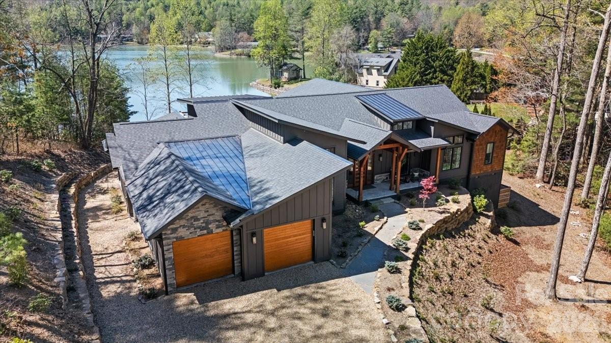 Panoramic lake and mountain views take center stage from this stunning property overlooking peaceful Eagle Lake. Designed to maximize the scenery, the home captures water views from nearly every room, blending modern lines with rich textures throughout. Enjoy cool mountain breezes from open decking with unobstructed sightlines, and step down to your private dock for easy access to trout- and bass-filled waters. Inside, a full chef’s kitchen anchors the home, while the primary suite offers a spa-like retreat with thermostat-controlled heated bathroom floors. Just minutes from Brevard, you’ll have access to hiking, biking, the Brevard Music Center, and the natural beauty of Pisgah National Forest and DuPont State Forest.