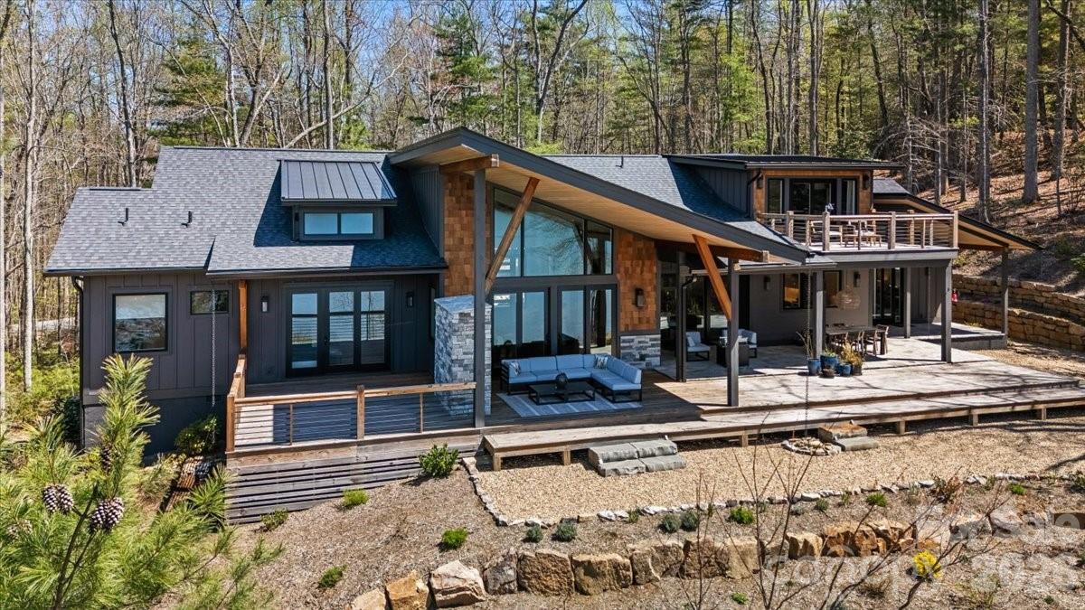 Panoramic lake and mountain views take center stage from this stunning property overlooking peaceful Eagle Lake. Designed to maximize the scenery, the home captures water views from nearly every room, blending modern lines with rich textures throughout. Enjoy cool mountain breezes from open decking with unobstructed sightlines, and step down to your private dock for easy access to trout- and bass-filled waters. Inside, a full chef’s kitchen anchors the home, while the primary suite offers a spa-like retreat with thermostat-controlled heated bathroom floors. Just minutes from Brevard, you’ll have access to hiking, biking, the Brevard Music Center, and the natural beauty of Pisgah National Forest and DuPont State Forest.