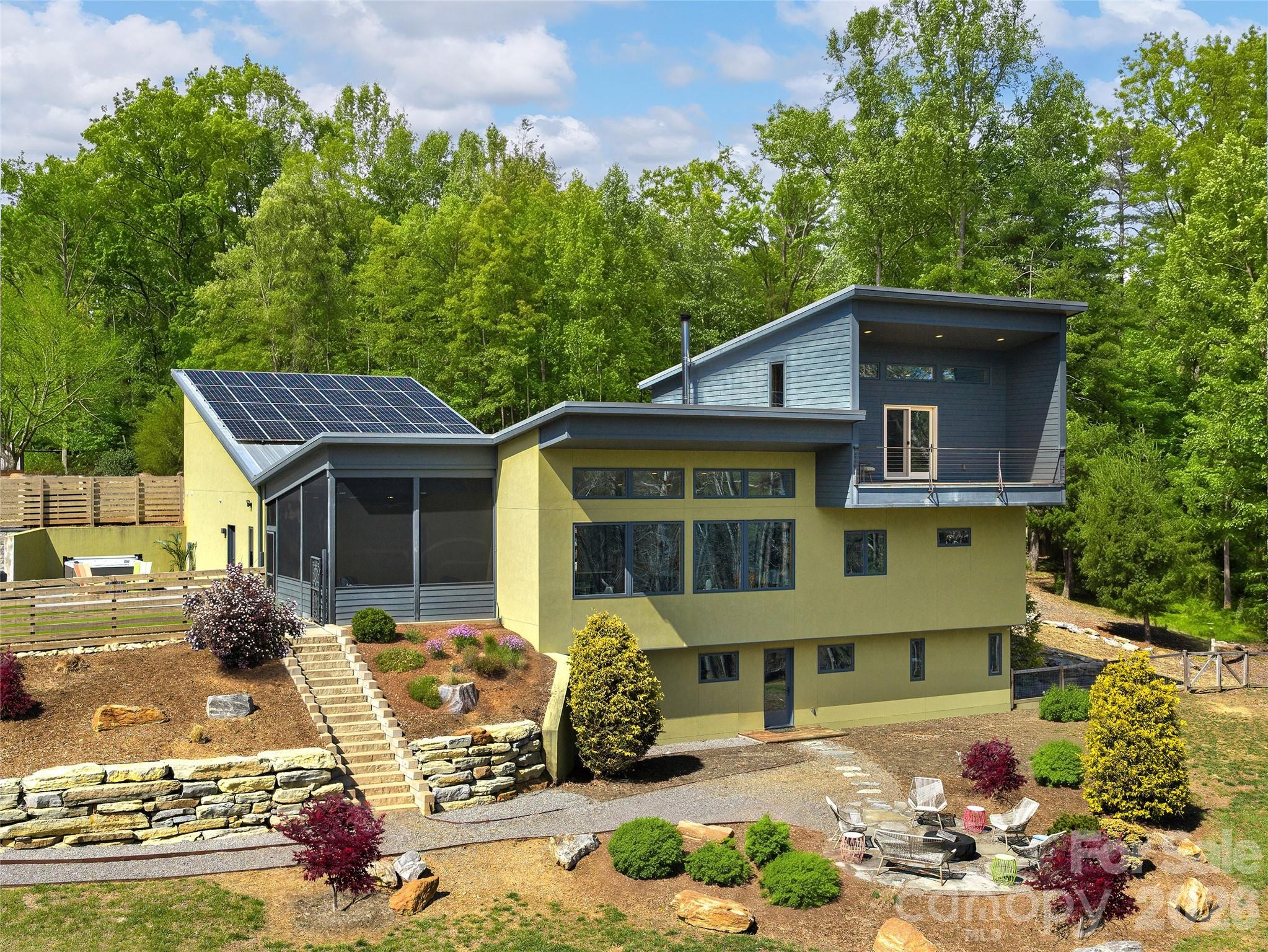 Some homes are built - this one was crafted with intention. Nestled in the pristine beauty of Asheville's historic Cane Creek Valley, this solar-powered architectural gem is unlike anything currently on the market: a seamless fusion of sustainability and genuine luxury that beckons the discerning buyer. Soaring ceilings, custom lighting, and stunning maple woodwork set the tone, while the chef's kitchen, complete with SieMatic German cabinetry, Thermador induction cooktop, steam and convection ovens, makes cooking feel like an event. The main level primary suite features a luxurious bath with double Hansgrohe rain showers and a spacious walk-in closet. A private ensuite loft with an Ipe balcony gives guests a world their own. On the terrace level, a versatile family room, TV room, and two bedrooms (one with Murphy bed) share a bathroom with a BainUltra airjet tub and a MrSteam shower. Outside, the private, gentle lot is immersed in nature with custom paver patios, hot tub, built-in fireplace, and pizza oven - the perfect backdrop to casual entertaining. Thirty-two solar panels, battery backup, triple-pane Kolbe windows, Sonos, Lutron, & Cat6. This home doesn't just look like the future, it runs like it. Five miles to Whole Foods, twelve miles to downtown Asheville. A lifetime away from ordinary.