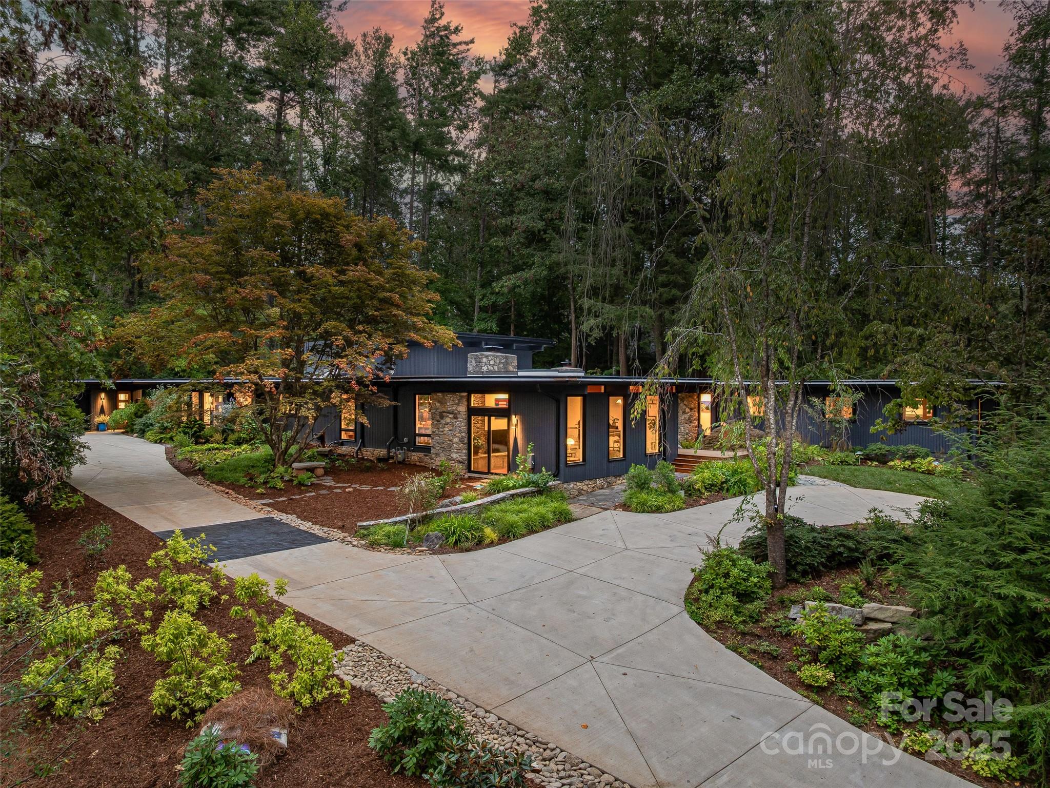 Originally built in 1966 by renowned Asheville architect Lawrence Traber, 5 Brookside is widely considered one of his finest mid-century modern works. Designed around Traber’s philosophy of harmony with nature, the home is set on 1.34 acres of lush gardens in a private, wooded setting—just minutes from downtown Asheville.
Meticulously and respectfully reimagined, the home blends iconic design with extensive high-end upgrades. Steel beam construction provides lasting structural integrity. Recent exterior improvements include fresh paint (2024), a double-thickness TPO roof with a 20-year warranty (2025), new gutters, and four new skylights that flood the interior with natural light.
Inside, the home features new Brazilian cherry hardwood floors, paneled columns, and new 8" baseboards throughout. Sierra Pacific windows enhance both aesthetics and efficiency. Comfort and reliability are ensured with a Generac whole-house generator, Rheem HVAC and heat pump system (2023) with five zones, a new air handler (2025), and a Navien high-efficiency tankless water heater with recirculating pump (2023). New sewer and water lines were installed in 2025.
The fully remodeled kitchen (2024) is a showpiece, featuring premium Fulgor appliances, a 48" stainless Sub-Zero refrigerator, and a newly added butler’s pantry. A separate laundry room with Miele appliances adds everyday convenience. A partially finished lower-level room offers flexibility for a home gym, music room, playroom, or office.
A dramatic two-story wall-of-glass Garden Room addition (2024) creates a striking connection to the outdoors and opens to an expanded back terrace. Outdoor features include a flagstone retaining wall, hidden drainage, a soapstone gardening shelf, and a welcoming stone patio ideal for entertaining.
The primary suite was fully renovated and expanded in 2025, creating a peaceful retreat with a luxurious new bath and a spacious walk-in closet with custom built-ins. Thoughtful lighting throughout highlights art and architecture, including select permanent installations with custom metal ironwork by local artisans Screaming Hot Iron.
Additional improvements include an expanded circular concrete driveway (2024) with new exterior lighting and numerous system upgrades that make this home as functional as it is beautiful.
A rare opportunity to own a thoughtfully modernized architectural landmark, 5 Brookside offers timeless mid-century design, exceptional craftsmanship, and a tranquil natural setting—just moments from the heart of Asheville.