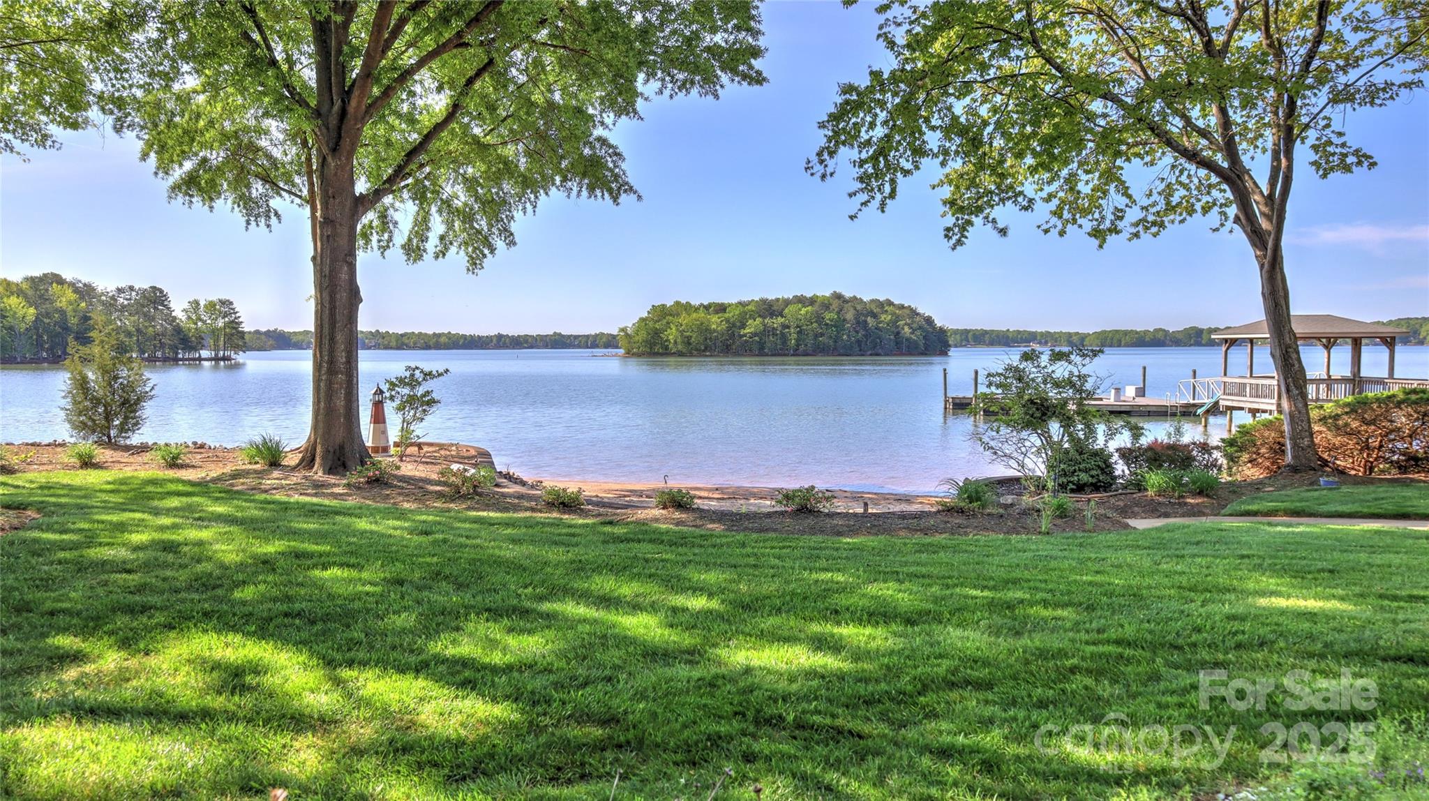 Own a slice of paradise in The Harbour at the Pointe with this well-maintained waterfront home offering stunning main channel views of Lake Norman. A grand foyer with  opens to a two-story great room with fireplace, built-ins, and floor-to-ceiling windows showcasing the lake. The main-level primary suite features lake views and a spacious en-suite bath. Upstairs offers charming bedrooms with en-suites, window seats, a loft, and ample storage. The finished basement includes a second owners suite, great room with gas fireplace, kitchenette, exercise room, hot tub room, and a waterview office. Enjoy a sandy beach, covered dock with boat and jet ski lifts, and a dredged swim area with slide. Relax on the screened porch, deck, or patio with gas grill hookup. Landscaped yard with irrigation, newer HVAC units, new septic pump, whole-house water purifier, generator, and more. Move-in ready with incredible potential—your Lake Norman dream awaits!