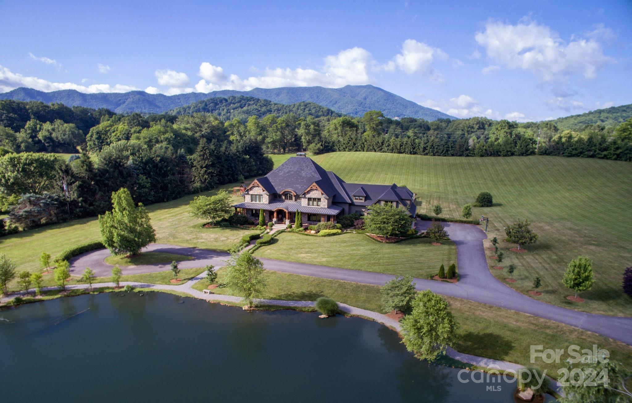 Willow Mountain Estate is located in the gorgeous countryside of Waynesville, minutes to the charming downtown. This impressive home sits on 11 level acres with a large trout pond and native rushing trout stream. Catch rainbow trout and prepare them in your inviting outdoor kitchen & dining area. Enjoy summer days outside at the pool surrounded by amazing mountain views and exquisite gardens. Enter this magnificent home through the grand foyer with beautiful hardwood floors leading you to the great room with a two-story wall of windows and stone fireplace. Thoughtful design with attention to flow in the design of this home, fantastic for entertaining! The kitchen, master bedroom and living room all open to the rear terraces and pool. The second floor offers spacious guest suites a theater, entertainment room and an intimate bar and lounge to gather at the end of a fun day together! PLUS - Barn/Garage/Workshop, Huge Pavilion, Organic Gardens & So Much More!!! High Speed Internet YES!
