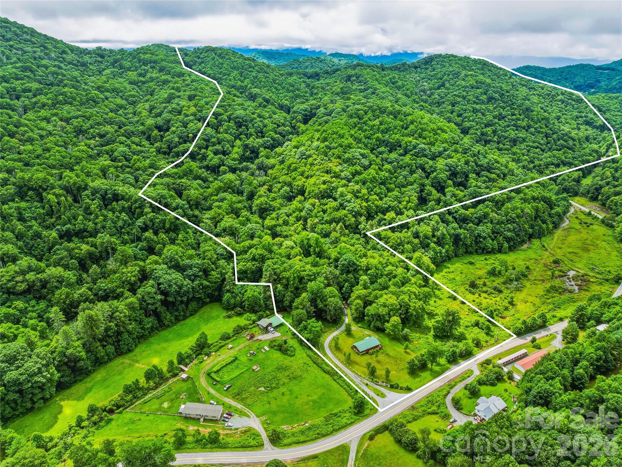Discover one of Western North Carolina's most extraordinary legacy properties. Spanning approximately 269 acres in the scenic mountains of Madison County, NC, this rare estate encompasses five existing residences, and offers an unrivaled combination of privacy, versatility, and long-term investment potential. Whether your vision is a private mountain retreat, equestrian estate, legacy family compound, boutique hospitality venture, corporate retreat, conservation property, or a thoughtfully planned development, this remarkable property offers the scale, valuable existing infrastructure, and natural beauty to bring it to life.
Enjoy breathtaking long-range mountain views, rolling pastureland, wooded hiking and ATV trails, abundant wildlife, unmatched privacy, and countless potential home sites throughout the estate. The existing residences provide immediate flexibility for extended family, caretakers, guest accommodations, or rental income while preserving incredible opportunities for future growth. 
Conveniently located just outside the charming town of Mars Hill, with easy access to Asheville, Hatley Pointe, Wolf Laurel, skiing, hiking, and year-round outdoor recreation, this is a once-in-a-generation chance to own one of Western North Carolina's most significant large-acreage mountain estates.

The property includes four move-in ready log homes plus an additional ranch-style residence, providing exceptional flexibility for multi-generational living, guest accommodations, staff housing, or income-producing rentals. Additional improvements include a large workshop/garage with an apartment, a picturesque pond, and a massive greenhouse, each ready to be restored. Over a mile of paved roads dissect the acreage with gated access on both the eastern and western boundaries. Underground utilities throughout the property provide a rare foundation for future expansion. Beyond the improvements, multiple rolling pastures give way to hundreds of acres of mature hardwood forest, where an extensive network of trails winds through peaceful valleys and along scenic ridgelines.
Please NO DRIVE BYS and do not disturb the tenants.