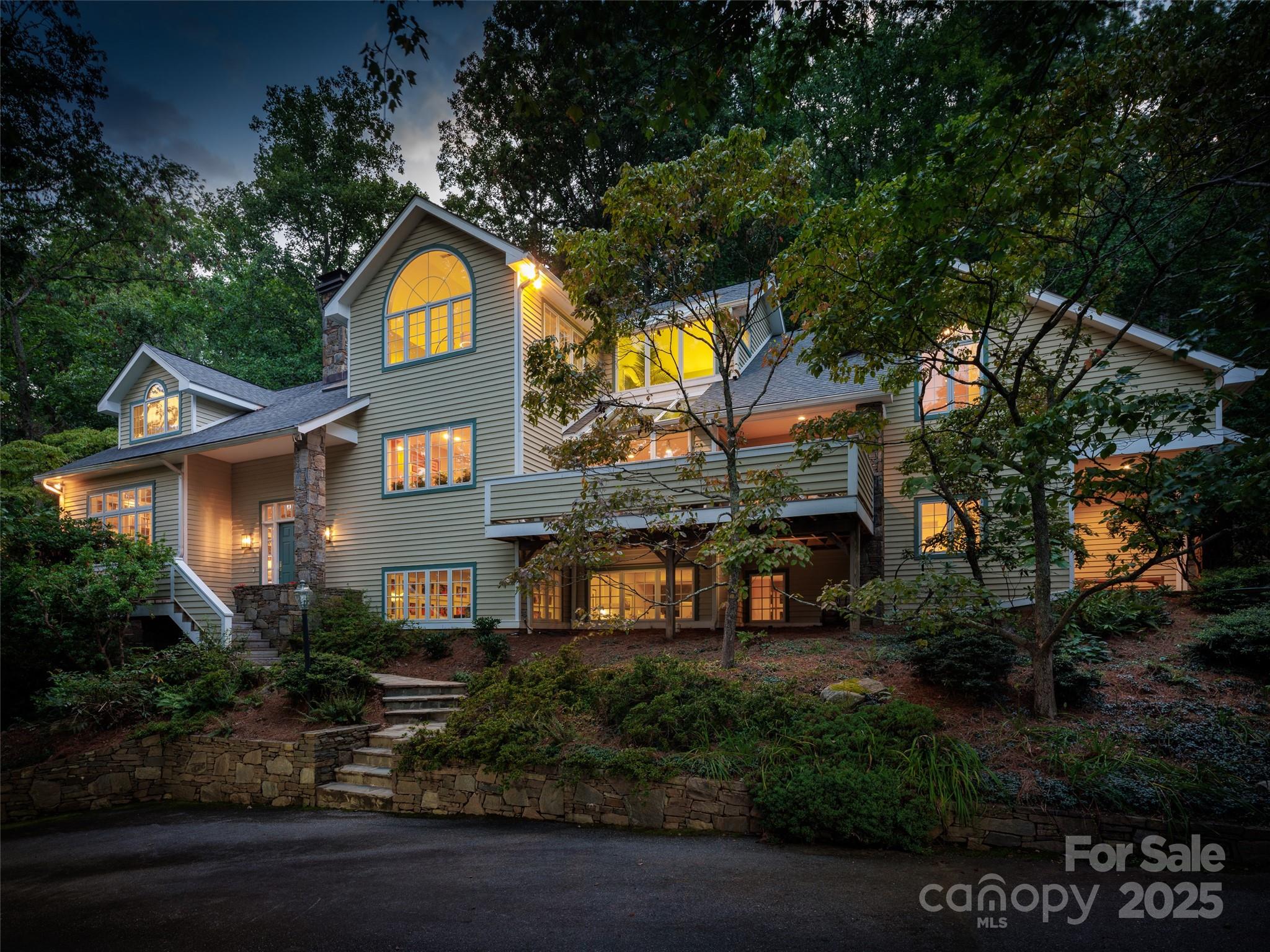First time on the market, this mountain home designed by architect Mark Sinsky feels like a retreat in the forest of the Blue Ridge Mountains yet having the convenience of being only three blocks from the country club of Asheville and 3 miles from the heart of downtown Asheville. Upon entering the two story foyer, there is an artisan stacked stone masterpiece separating the formal living and dining room. With built-in shelving, a wooden ceiling, exposed beams and wood burning fireplace, this room begs you to enjoy your morning coffee on the oversized window seat while watching the dappled eastern light come pouring in. Vaulted ceilings are a trademark of this home and the family room is no exception. Family and friends can gather around the wood burning stove while keeping the chef company in the adjoining kitchen featuring top of the line appliances including Wolf induction cooktop, dual Thermador ovens, dual Miele dishwashers and a sub-zero refrigerator. The expansive primary suite is an oasis of tranquility.