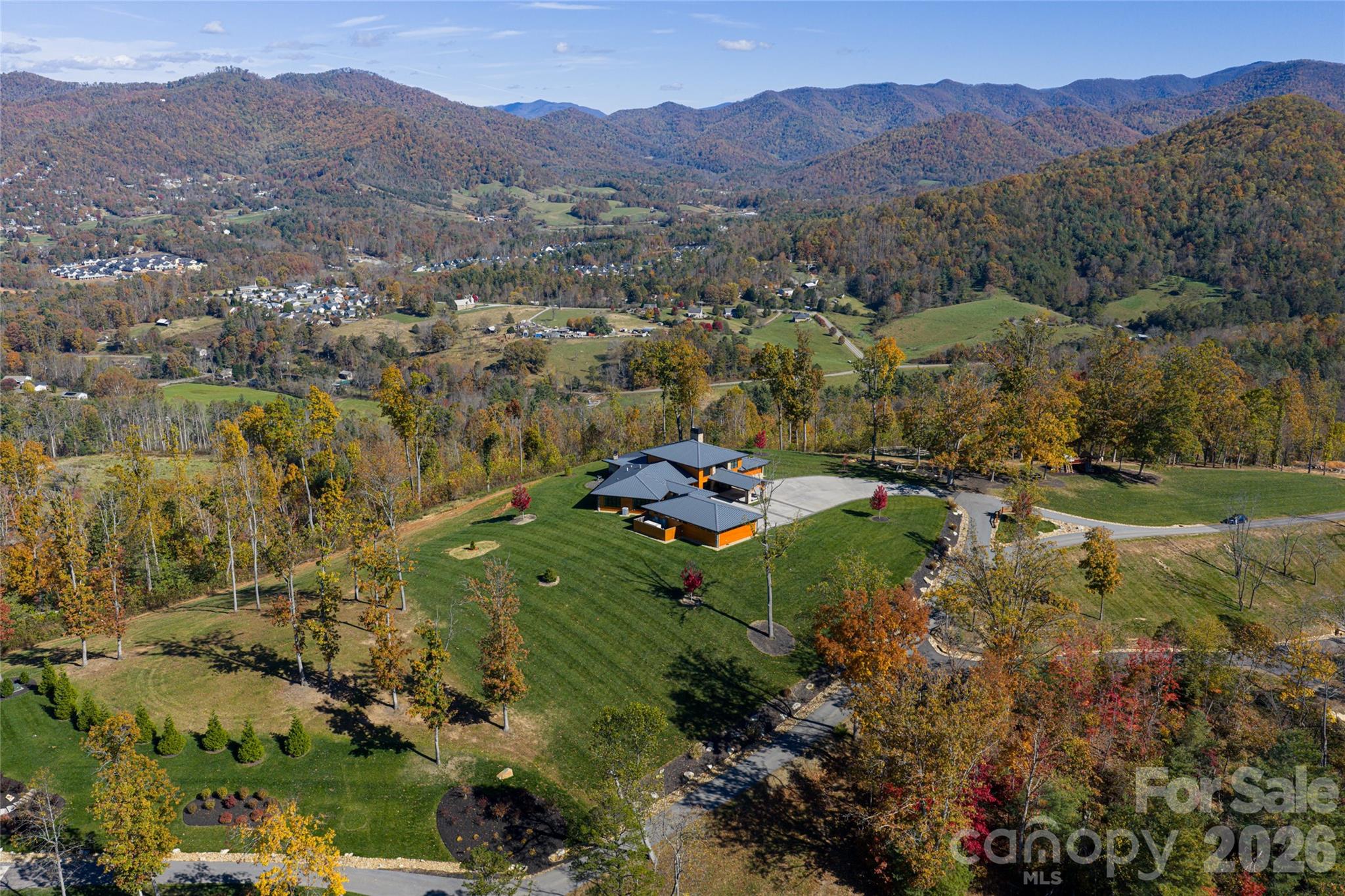 Spanning 51.31 acres in the heart of the Reems Creek Valley, this exceptional mountain estate combines a luxury residence with two adjoining parcels to create a property of uncommon scale, privacy and versatility. Offering long-range mountain views, a private pond, extensive usable acreage and multiple future homesites, the assemblage presents a rare opportunity to establish a legacy estate just minutes from downtown Weaverville and a short drive from Asheville. Thoughtfully positioned to capture sweeping mountain vistas from nearly every room, the residence was designed for everyday comfort and effortless entertaining. Hardwood floors flow throughout an open-concept floor plan anchored by a spacious great room and a chef's kitchen appointed with a quartzite island and a premium appliance package featuring Sub-Zero, BlueStar, Wolf and Miele appliances. A formal dining room with a striking stone accent wall provides an elegant setting for gatherings, while the primary suite serves as a private retreat complete with its fireplace and spa-inspired bath. Expansive windows frame the surrounding landscape, creating a seamless connection between the home and its mountain setting. Outdoor living is equally impressive, highlighted by a 56-foot covered rear porch with a wood-burning stone fireplace, generous entertaining space and a hot tub overlooking the long-range views beyond. Additional features include a detached climate-controlled three-car garage configured with a gym space, a whole-home generator and an irrigation system. The adjoining acreage transforms the property into something far beyond a traditional mountain home. One parcel offers an outstanding view homesite with the rare ability to accommodate a one-level residence while enjoying long-range mountain views. The second parcel features gently rolling wooded terrain, a picturesque pond with dock, and a substantial outbuilding used for tractor and equipment storage. Together, the combined acreage provides exceptional flexibility for a guest house, family compound, equestrian pursuits, recreational amenities, private trails, additional residences or simply preserving an extraordinary buffer of protected land around the main home. Access throughout the property is effortless via a wide, gently graded private gated road, eliminating the steep approaches often associated with mountain living. Whether envisioned as a private retreat, multigenerational compound or legacy property to be enjoyed for generations, the combination of a luxury residence, panoramic mountain views, private pond, substantial outbuilding and more than 51 acres of usable land is exceptionally difficult to replicate in today's market.