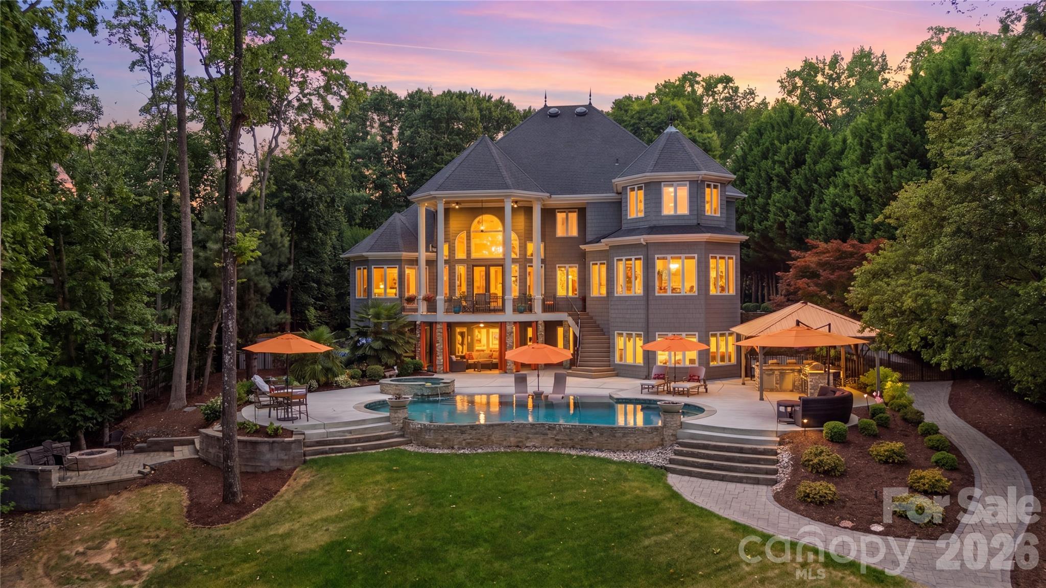 Nestled along the shores of Lake Norman, this extraordinary 7,452 square foot estate redefines waterfront living. Designed with both grandeur and livability in mind, the interior unfolds across a thoughtfully curated floor plan that balances impressive scale with genuine warmth. Four generously proportioned bedrooms offer retreats of absolute comfort and privacy. Six impeccably appointed bathrooms elevate the everyday routine into something far more indulgent, featuring premium fixtures and spa-inspired finishes that soothe as much as they impress. A three-car garage on the main level provides effortless convenience and ample space for vehicles, lake toys, and everything that accompanies an active waterfront lifestyle.  The living spaces are nothing short of spectacular. Soaring ceilings amplify the sense of openness, while expansive walls of glass frame uninterrupted views of Lake Norman, turning the water itself into the home’s most stunning design feature. Whether bathed in the golden light of a Carolina morning or the soft hues of a lakeside sunset, every room offers a connection to the outdoors that feels both intentional and inspiring. The layout moves with effortless grace from intimate sitting areas to sweeping entertaining spaces, accommodating everything from quiet evenings at home to lavish gatherings with equal sophistication. The thoughtfully finished basement adds a remarkable layer of versatility to this already exceptional home. A fully appointed multigenerational suite provides independent living quarters offering privacy and comfort without sacrificing connection to the main residence. A dedicated garage space rounds out the lower level, perfectly sized for a golf cart, hobby workshop, or additional storage, a practical luxury that serious lake living demands. Step outside and the estate truly comes into its own, making it a natural gathering point between the custom firepit and saltwater pool. The resort-style saltwater pool serves as the centerpiece of an outdoor living experience that is as functional as it is stunning and perfectly positioned to capture the lake breeze and afternoon sun. The fully equipped outdoor kitchen is a chef’s dream realized under open skies, complete with everything needed to host al fresco dinners, weekend brunches, and everything in between without ever missing a moment with your guests. The waterfront experience extends far beyond the shoreline. An impressive 882 square feet of dock entertainment space provides a stunning platform for lakeside gatherings, sunset cocktail hours, and lazy summer afternoons spent entirely on the water. The dock is fully equipped for the serious water enthusiast, featuring a dedicated boat lift and a dual jet ski lift, ensuring your vessels are protected, accessible, and ready to launch at a moment’s notice. Whether you’re pulling away for a sunrise cruise or returning from an afternoon on the lake, every departure and arrival feels like an occasion. Beyond the immediate amenities, the private waterfront setting grants direct access to one of North Carolina’s most beloved and expansive lakes. Lake Norman offers world-class boating, fishing, paddleboarding, and leisurely sunset cruises just steps from your back door. Truly a lifestyle that blends adventure with relaxation, as only true waterfront living can deliver.