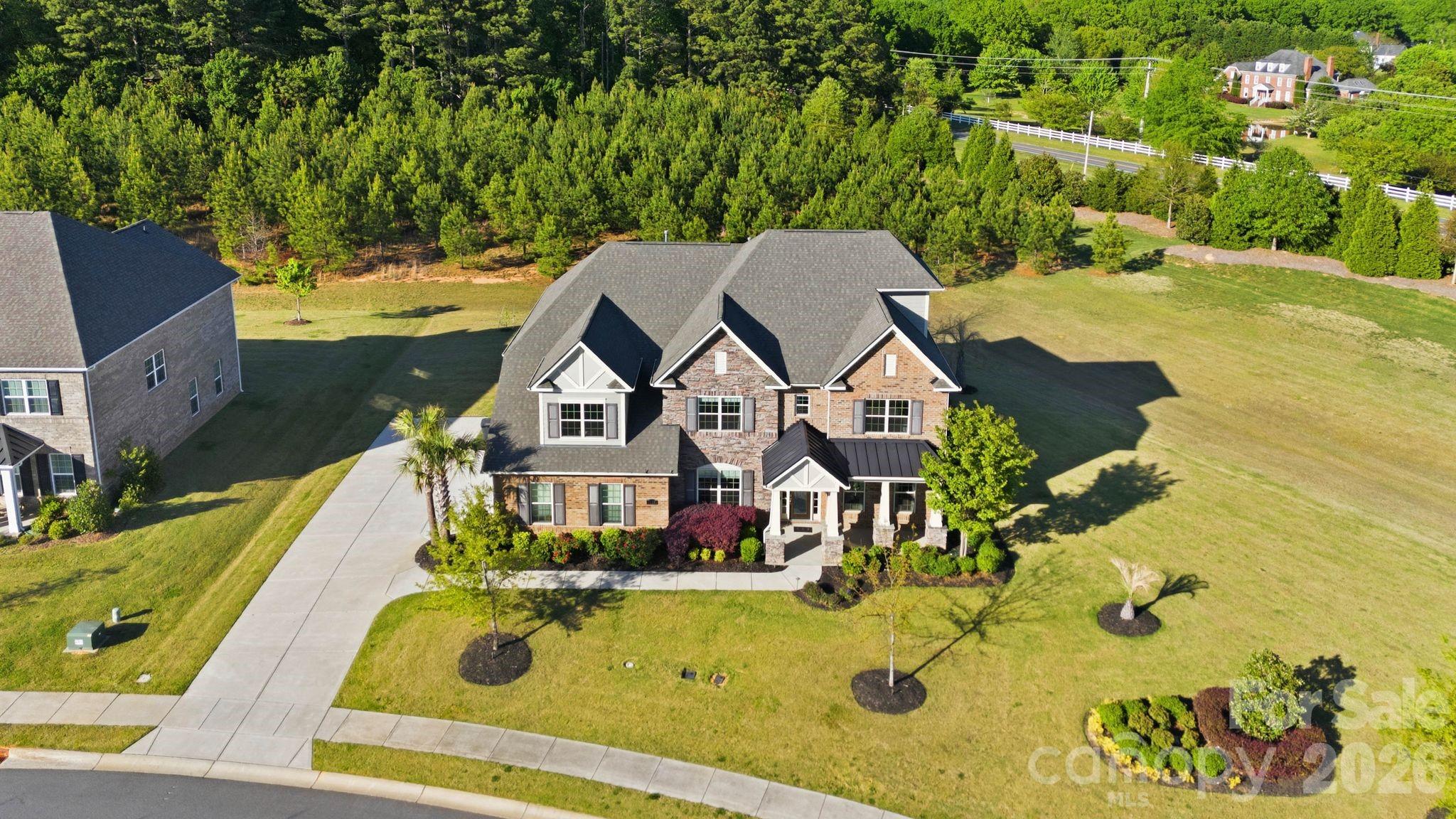 Situated in the desirable Weddington area, this former model home showcases a seamless blend of thoughtful design, quality craftsmanship, and modern comfort. From its impressive curb appeal and side-load three-car garage to the level backyard, with views of the woods this home offers both presence and privacy.
A welcoming foyer with 10-foot ceilings, engineered hardwood flooring, and detailed millwork leads to well-appointed formal living and dining spaces, as well as a spacious great room featuring coffered ceilings and a gas fireplace. The kitchen is designed for both functionality and entertaining, complete with an oversized island, quartz countertops, stainless steel appliances, farmhouse sink, walk-in pantry, and custom cabinetry. The adjacent covered patio and firepit create an easy transition to outdoor living.
The main level includes a desirable guest suite with a full bath. Upstairs, the primary suite offers a private retreat with a sitting area, balcony access, dual walk-in closets, direct laundry access, and a well-appointed bath. Secondary bedrooms are generously sized, each with its own en-suite bath. A flex space room could be a space for crafts or another office.  A bonus/media room with custom finishes and surround sound, along with a third-floor flex space, provide additional versatility for a variety of needs.
Additional features include a finished garage, irrigation system, and numerous designer upgrades throughout. Conveniently located near Waverly, Rea Farms, and Blakeney, with access to local amenities including fitness centers and recreational facilities. The expansive lot offers potential for a future pool or outdoor living expansion. Award winning schools.