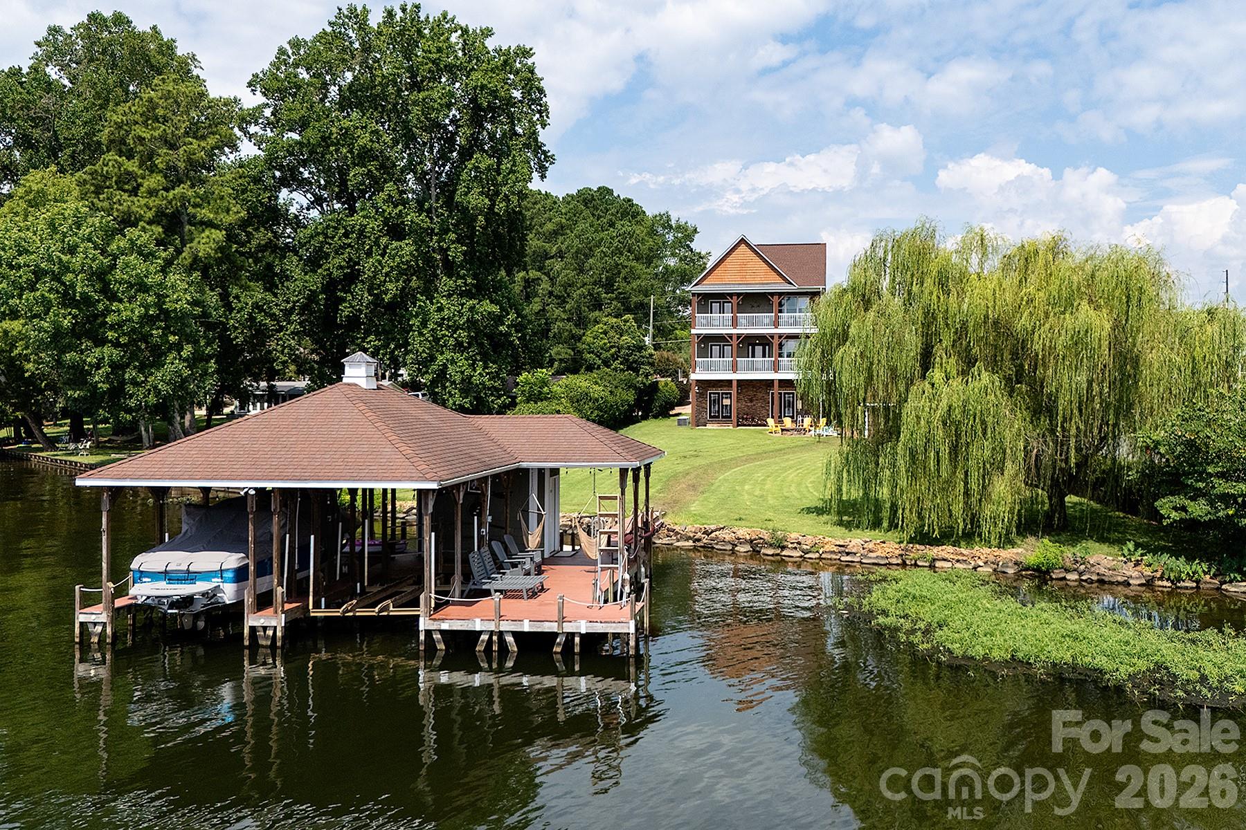 Luxury Lakefront Retreat with Strong Short-Term Rental Potential—Experience the art of lakeside living in this exceptional waterfront sanctuary featuring approximately 85 feet of pristine shoreline and breathtaking, year-round water views. This custom-built home blends warmth and sophistication, with a stunning stone-accented fireplace anchoring the main living space, an open-concept layout ideal for entertaining, and expansive windows that showcase the beauty of the lake. The primary suite offers a private escape with direct balcony access, serene water views, and a spa-inspired bath with a soaking tub. Upstairs, two additional bedrooms and two flexible sleeping spaces provide comfort for family and guests, while a spiral staircase leads to a lower-level retreat complete with a spacious recreation room, second kitchen, and wet bar—perfect for entertaining or extended stays. Outdoor living is equally exceptional, with multiple covered balconies, a lakeside fire pit, and a private dock equipped with a boat lift and personal watercraft lift for effortless days on the water. Whether enjoying quiet mornings overlooking the lake or entertaining at sunset, this home delivers an unmatched lifestyle. With strong short-term rental potential, this property offers a wonderful opportunity to enjoy luxury lake living while generating income.