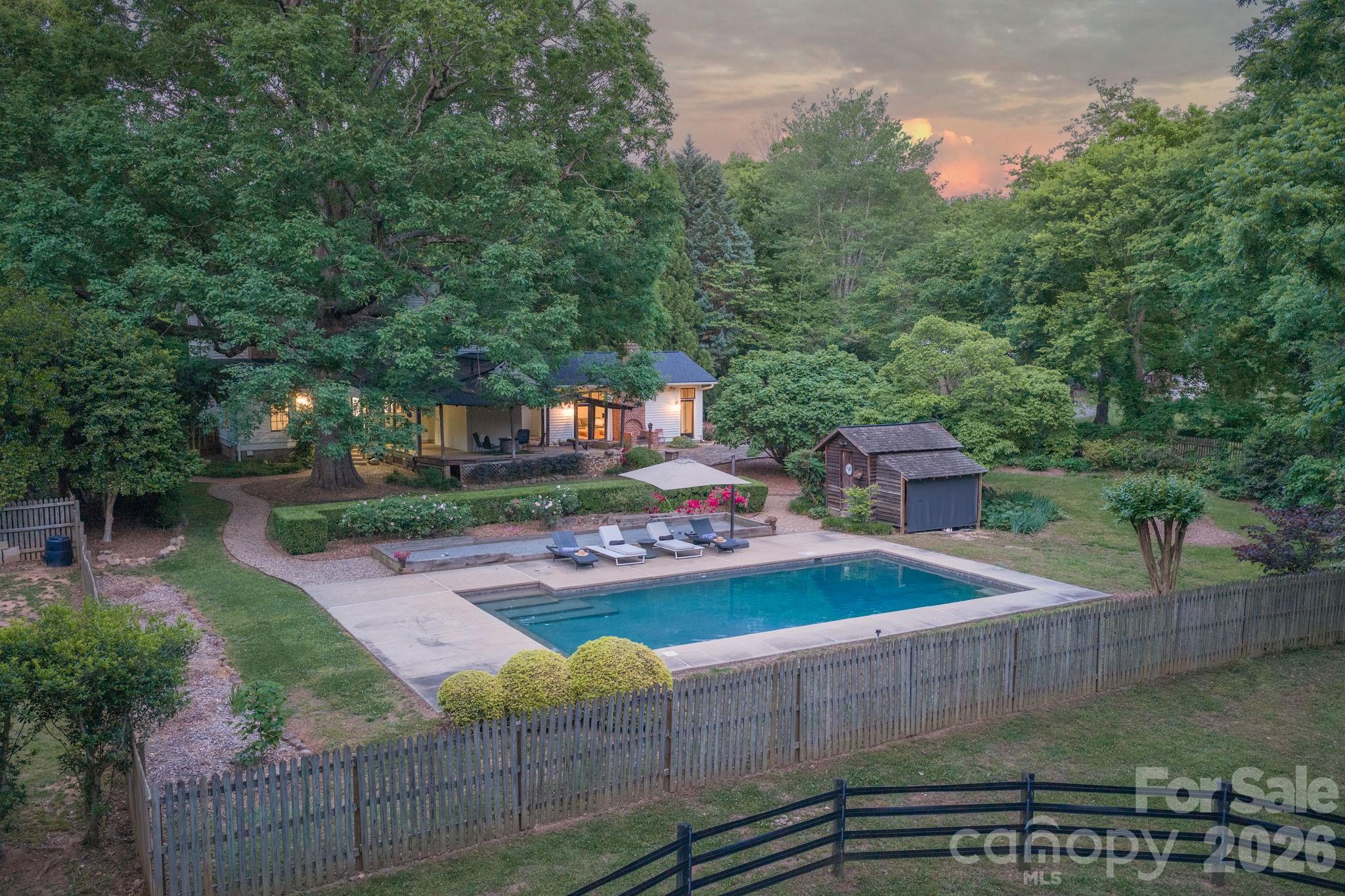 This extraordinary Victorian-era farmhouse, known as the McElroy House (c. 1883), seamlessly combines historic charm with modern luxury on 5 acres of pristine land. Unlike the typical and conservative I-house architecture of the time, the McElroy House is an outstanding example of the T-shaped two-story farmhouses built after the Civil War. The restored home bridges the gap between period significance and modern, functional living and includes the creation of a designer gourmet kitchen ideal for entertaining, as well as updated bathrooms. The incremental renovations occurred while preserving character, the 4-bedroom home boasts original hardwoods, ornate woodwork, a stunning staircase, 8 fireplaces (1 functional with woodstove insert) and outdoor living spaces ideal for morning coffee or evening breezes while enjoying the farm and animal views. 
The grounds are shaded by mature oaks and like the home, have a mixture of historical and modern elements featuring curated landscaping designed and created by a Master Gardener, a saltwater in-ground pool, bocce ball and hobby farm amenities built to accommodate farm animals of your choice with fencing, pastures, and a traditional barn. Adjacent to the home is a garage wired to charge electric vehicles. A fieldstone chimney stands behind the home (perhaps the remains of a summer kitchen). Nearby a tack house (now used as a tool/pool shed) stands on granite slabs. In the background is an 8-stall traditional barn with 2nd floor hay loft and adjoining chicken coop, all complemented by a round pen and Ramm cross-fenced pastures, ideal for equestrian/farm animal use.
Situated in the Lake Norman area, the property is near Latta Nature Preserve, offering easy access to 16 miles of equestrian, hiking, and biking trails. Enjoy peaceful country living just minutes from Birkdale Village, I-77/I-485, and a short drive to Charlotte and Douglas International Airport. 
For generations the McElroy Home has been occupied by the family and direct descendants. Only the third non-family owners, the current owner as well as the previous, were outstanding stewards of this historical gem. They understood that they were the “temporary keeper” balancing the preservation of the home’s original character with the need for modern functionality for future generations. Currently searching for the next steward of the home and land, one that wants to embrace history and a time when we lived off the land, spent the majority of our time outdoors working the gardens, taking care of the livestock and putting food on the table. Considering a lifestyle reminiscent of times that have passed us by, and a more natural lifestyle yet appreciate access to modern amenities and cultural activities, McElroy House and farm may be the answer. Detailed Brochure Available.