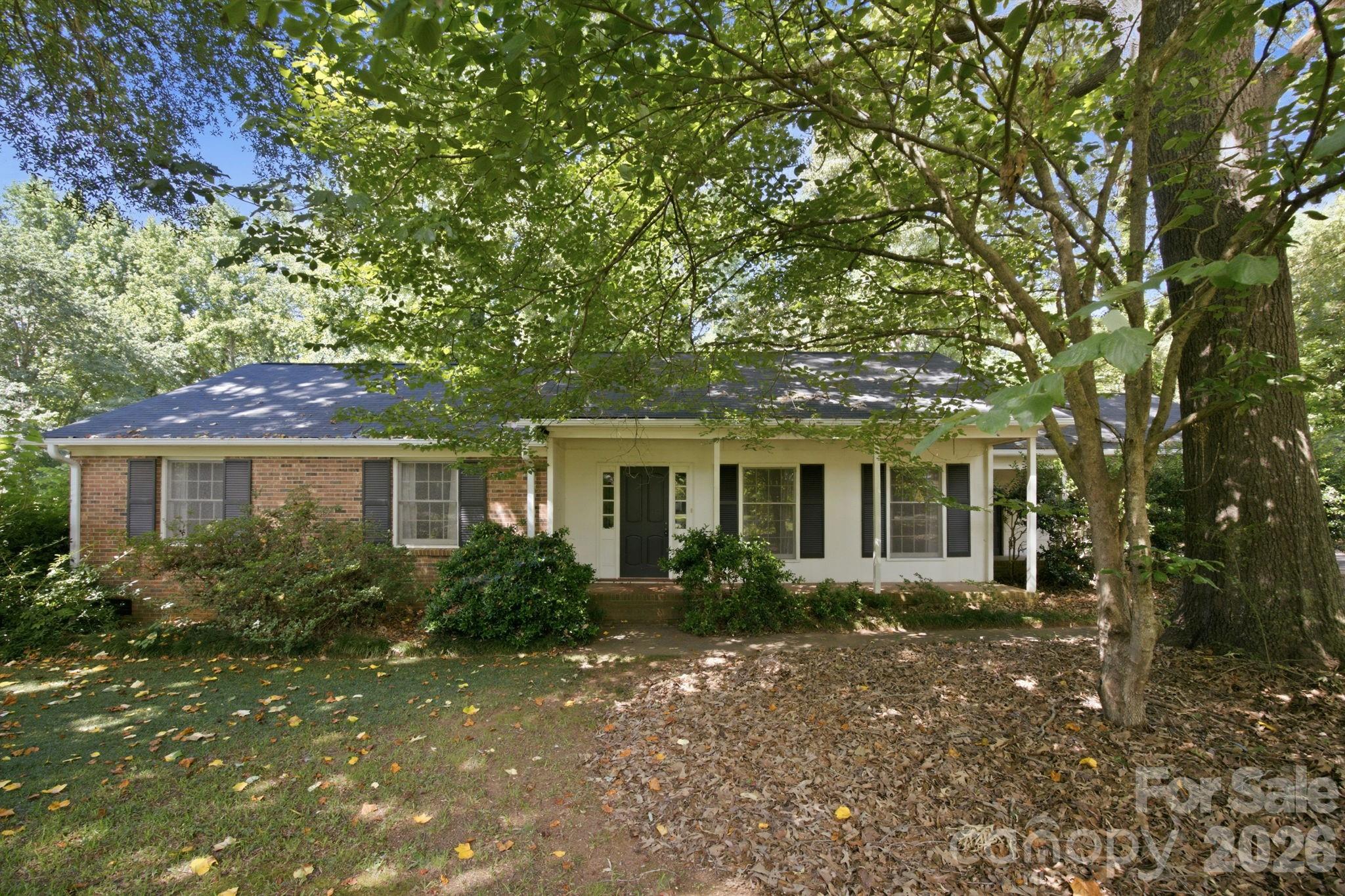 Welcome to this classic ranch home nestled on approximately 0.45 acres with no HOA restrictions. This charming property invites you to unleash your creativity and make it uniquely yours. Sold as-is, yet brimming with potential, you’ll adore the nostalgia of the features from decades past. Welcoming front porch with room for multiple seating areas. This home has wood floors throughout much of the home, which provide a timeless foundation for any design style. The generous layout includes a formal living room, formal dining room, large kitchen with breakfast area, and a den with a wood burning fireplace. The primary bedroom has wood floors and a private bath with step-in shower. The secondary bedrooms also have wood floors. The laundry area is inside the home, has cabinetry and the washer and dryer remain. The two-car covered carport provides convenient parking and features a locked storage area. While some yard work will be necessary to restore the yard to its formal charm, there is plenty of space to create a lovely outdoor area. The rear yard is partially fenced and has a patio area off of the den.  The property is conveniently located to UNCC, I-485 and I-85. A family member mentioned there is an old oil tank buried in the rear yard, but doesn’t have any information on it. They also said the home has a Trane Gas Pack, the roof was put on in 2024, they noticed a limb made a hole in the ceiling of the storage area off of the carport, and they don’t know where the water heater is located, they believe it may be in the crawl space. The home’s vintage charm is evident throughout, offering great potential to personalize and update. This home is priced to sell, don’t miss the chance to transform this hidden gem into your personal retreat.
