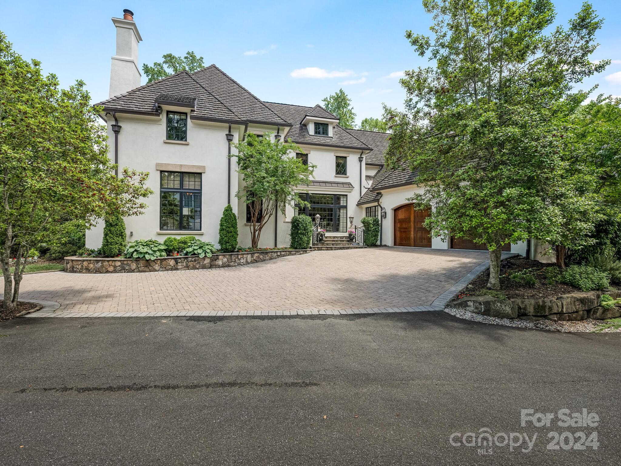 Tucked away in the heart of Eastover--overlooking Catawba Conservancy Land-this French country home blends charm with all of today's conveniences. The open floor plan is designed to flow naturally for easy entertaining.
Main level primary suite has an oversized bath, dual walk in closets and direct access to the terrace. The chef's domain features  a large island, professional grade appliances, pantry, dedicated breakfast area and bar. Coffered ceilings, built-ins, and the stone fireplace accent the great room position as the heart of the house.
The paneled office with fireplace and beamed ceiling is both inviting and is ideally  positioned to shield  the sounds of an active house.

Heading to the upper level--all bedrooms are en suite with oversized closets. Ample storage throughout--both walk in and walk up options.