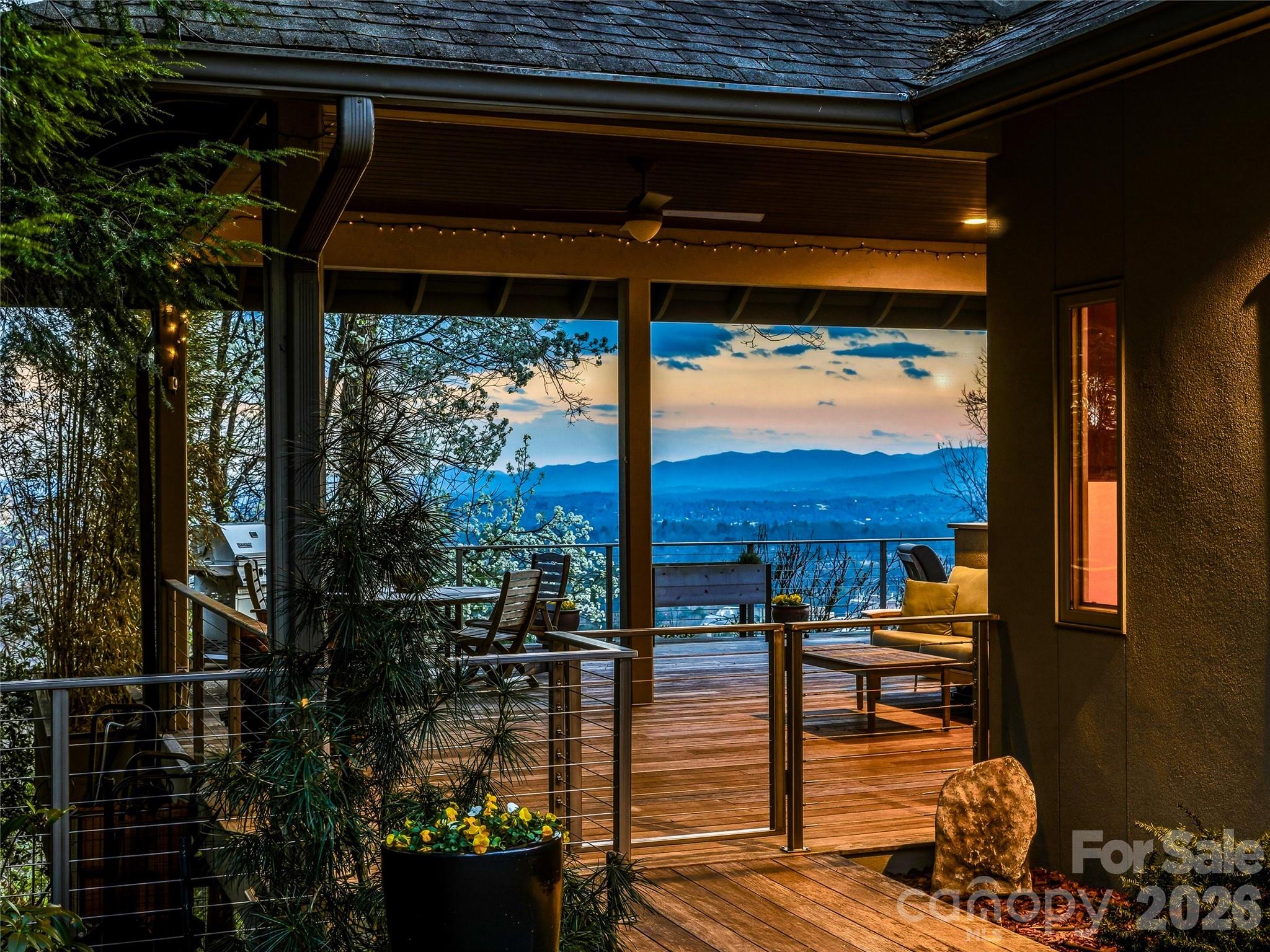 The view is immediate—and unforgettable. From the moment you step inside, downtown Asheville unfolds below you, framed by layers of Blue Ridge Mountains that shift with the light from sunrise to sunset.
Designed by noted architect Bill Ashe to live in harmony with its setting, this home captures the panorama from nearly every room, filling the interiors with natural light and an ever-present sense of place. In the main living areas, floor-to-ceiling windows in the living and dining rooms create a dramatic backdrop—blurring the line between indoors and out while seamlessly connecting to the open kitchen for effortless everyday living and entertaining.
Expansive covered and open-air terraces extend the experience outdoors—perfect for morning coffee above the city, golden-hour gatherings, and evenings under a painted mountain sky.
The main level offers true ease of living with a bright, open floor plan anchored by a spacious kitchen featuring a gas range, generous prep space, and a peaceful view over the landscaped gardens. A butler’s pantry and dedicated kitchen office add thoughtful functionality without compromising flow.
The primary suite is a private sanctuary on the main level, opening to its own deck and offering two walk-in closets and a spa-inspired bath—where even the soaking tub is positioned to take in the mountain backdrop.
A richly appointed library or media room with custom built-ins, a garden-access office, and a large laundry room complete the main level.
Upstairs, two bedrooms, an office with built-ins, and a generous family room provide comfortable separation for guests, while additional flexible space adapts easily to your needs.
Set on a private, beautifully maintained homesite, the level fenced garden, greenhouse, and ideal southern exposure create a rare combination of usability and beauty—enhanced by solar power for modern efficiency.
A large two-car garage with a third bay accommodates a sports car, a golf cart, or recreational gear, and offers convenient access to the main level.
All of this, just minutes from downtown Asheville—yet a world apart.
A home defined not just by its views, but by how it makes you feel living in it.