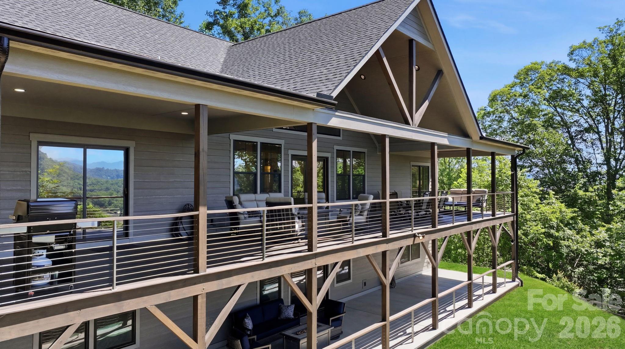 Mendleson Homes, a Parade of Homes award-winning custom home builder, is proud to present one of the most exceptional mountain-modern retreats in all of Western North Carolina. Prepare to be completely blown away as you enter the sought-after Rock Bridge community, crossing the freshwater creek before ascending to the top of the mountain, where you'll discover your dream home offering one of the most extraordinary mountain views in all of Waynesville. You will be impressed by the privacy and exceptional craftsmanship on this 1.33-acre, 3-bedroom (plus bonus room), 3.5-bath home featuring a bright, open-concept layout, vaulted ceilings, expansive windows, and beautiful luxury vinyl plank (LVP) flooring throughout. No expense was spared in the construction of this remarkable home. The driveway was paved, and the access road near the home was repaved as of May 27, 2026. The chef's kitchen is a true centerpiece, showcasing custom cabinetry, quartz countertops, a spacious island, a convenient microwave drawer, and seamless flow into the main living area—perfect for everyday living and entertaining. The fully finished walk-out lower level expands the living space with a private basement kitchenette featuring its own refrigerator and countertop microwave, making it ideal for guests, recreation, or multigenerational living. Two refrigerators, along with all appliances, convey with the home. The breathtaking Blue Ridge Mountain views draw you outside from nearly every room. Enjoy effortless indoor/outdoor living with an impressive 800-square-foot covered wraparound deck on the main level, while the lower level opens to an equally expansive 800-square-foot covered concrete patio, providing exceptional space for relaxing and entertaining year-round. Designed for comfort and efficiency, the home features separate HVAC systems for the upper and lower levels, including two heat pumps, two central air units, and separate water heaters. A fenced yard and detached garage complete this exceptional property. Being sold fully turnkey with brand-new high-end furnishings and all appliances included, this stunning mountain-modern retreat offers a rare move-in-ready opportunity in the heart of Western North Carolina. Ownership available after October 1, 2026. Occupancy negotiable beforehand. Conveniently located just 15 minutes from award-winning Historic Downtown Waynesville, 20 minutes from Harrah's Cherokee Casino, and 30 minutes from Asheville.