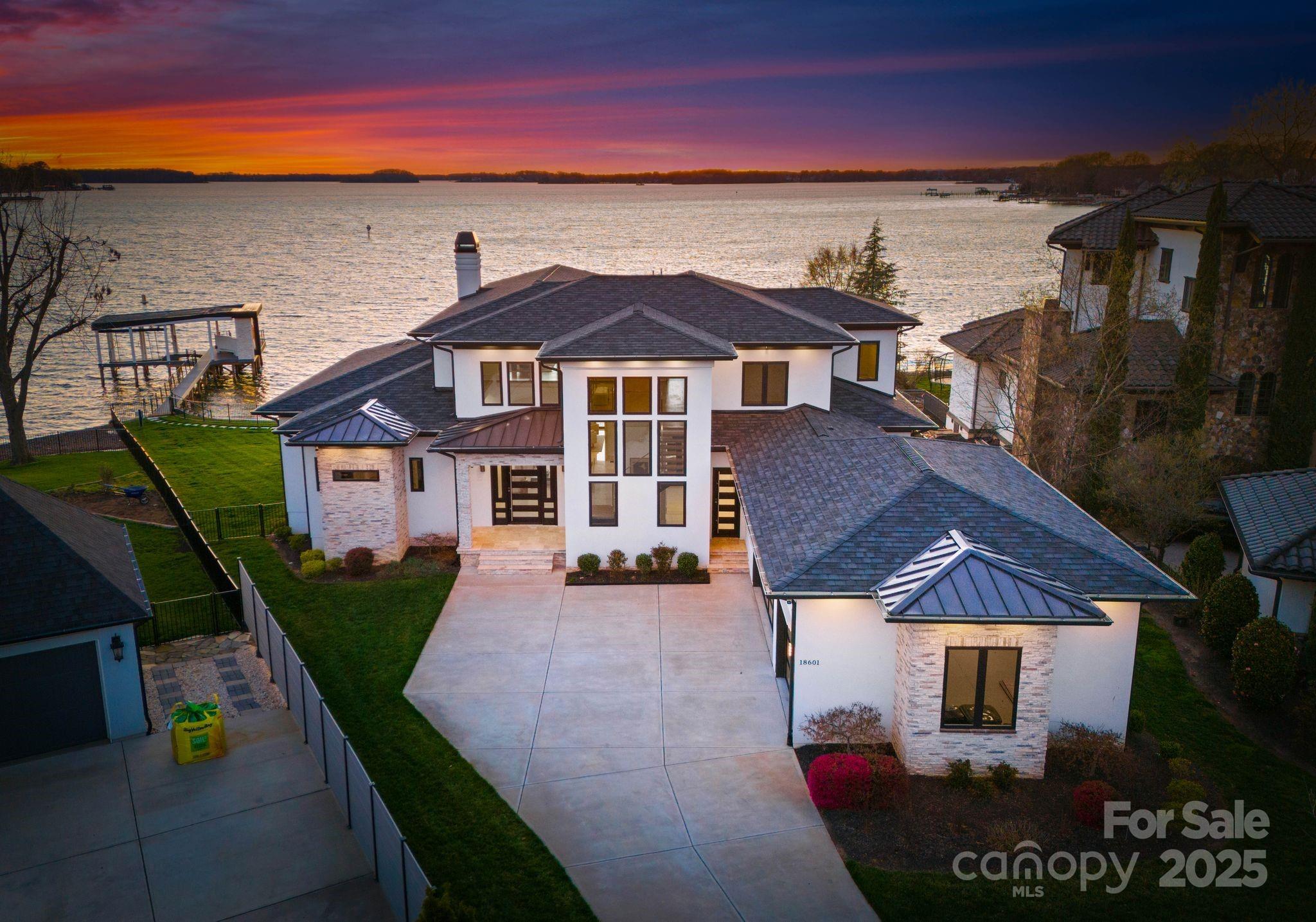 Experience luxury at its finest, with this modern build residence on Lake Norman boasting breathtaking views of the lake and sunsets. The first floor features Italian porcelain tile flooring throughout the multiple living/dining spaces, an entertainer's dream. The kitchen has Cambria Quartz countertops, Subzero refrigerator and much more. Multiple sliding glass doors open up to the back patio and heated, salt water pool overlooking the lake. Relax in the tranquil, primary suite located on the first floor with gorgeous views. Primary bath features luxe finishes, free-standing soaking tub with jets, custom built-in closets, Italian porcelain tile floors and shower. Fenced back yard, sandy beach, custom dock built in 2023 w/seating area & boat lift. Attached 3 car garage is heated and cooled year round. New Roof in 2024/2025 with GAF Camelot II Charcoal Shingle. Control-4 lighting system, automatic shades in main living spaces, primary bedroom and upstairs bonus/office.