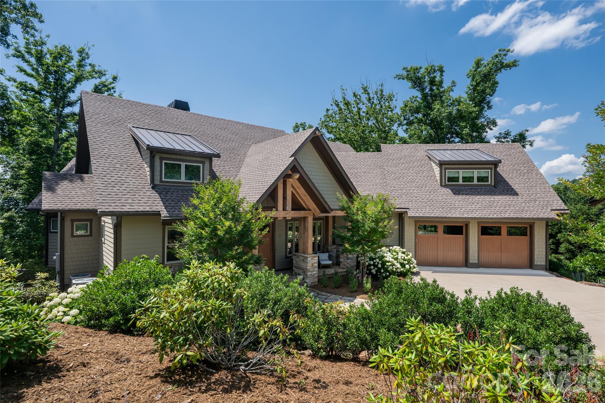 Perched within the sought-after Ventana community, this exceptional Arts and Crafts residence captures breathtaking long-range mountain vistas and offers a seamless blend of refined luxury and relaxed mountain living. Designed for grand entertaining and everyday comfort, the thoughtfully crafted open floor plan unfolds around a stunning great room featuring soaring vaulted ceilings and a dramatic floor-to-ceiling stone fireplace. The gourmet kitchen is a chef’s dream, appointed with granite countertops, double ovens, dual pantries and a wine refrigerator, flowing effortlessly into the dining area and main living spaces. Walls of glass invite the outdoors in, opening to an expansive covered deck where sweeping mountain views create an unforgettable backdrop. Gather around the outdoor fireplace on the deck and enjoy year-round alfresco living while taking in the beauty of the surrounding Blue Ridge landscape. The spacious primary suite serves as a private retreat, complete with direct deck access, a luxurious bath and an expansive walk-in closet. A second bedroom and full bath on the main level provide comfort and convenience for guests, while an additional upstairs bedroom and generous storage area offer flexibility for family and visitors. The lower level is designed for recreation and relaxation, offering two additional bedrooms, two full baths, a welcoming family room, kitchenette and recreation space. Go outside to the lower-level deck, where a private hot tub awaits beneath the stars and mountain skies. Beautifully landscaped grounds enhance the home's natural setting with vibrant hydrangeas, mature rhododendrons, and a charming stone pathway that meanders through the gardens, creating a sense of serenity and connection to nature. While offering the peace and privacy of a mountain retreat, this exceptional home is conveniently just minutes from vibrant downtown Asheville and the charming town of Weaverville. Residents enjoy easy access to acclaimed local restaurants, boutique shopping, galleries, grocery stores and everyday conveniences, making it the ideal balance of seclusion and accessibility. Offering extraordinary views, exceptional indoor-outdoor living, and timeless Arts and Crafts architecture, this remarkable Ventana residence is a mountain sanctuary designed to be enjoyed in every season.