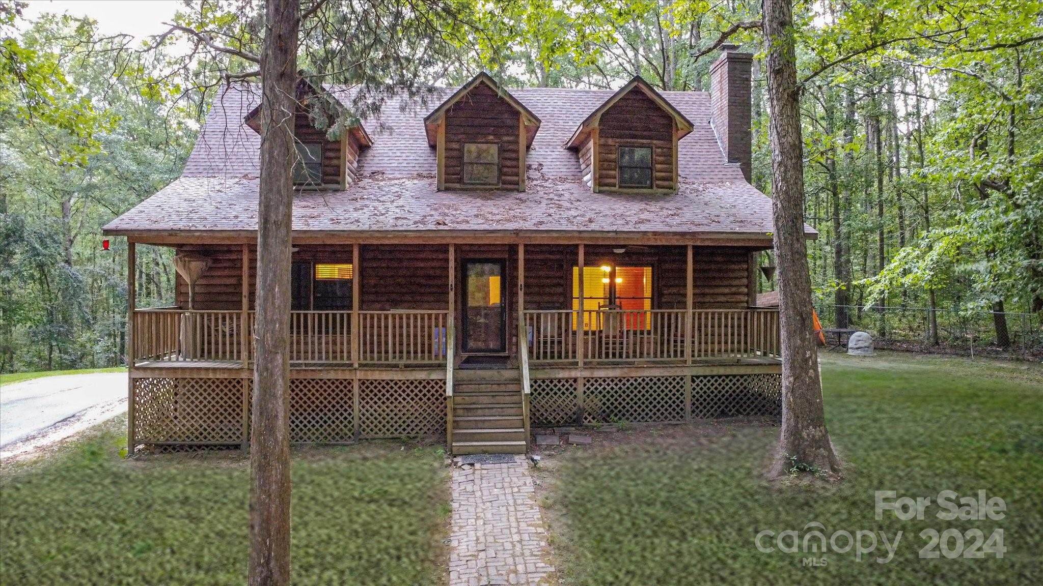 Nestled on a serene 2.5-acre wooded lot, this charming cabin offers rustic charm and modern convenience. Just minutes from town, it provides a tranquil escape with all the amenities you need for a comfortable lifestyle. Enjoy beautiful views from the front porch and back deck, where you can relax and take in the natural beauty. The cabin is bordered by a gentle creek, adding to the serene atmosphere. The living room features a cozy wood-burning fireplace, perfect for chilly evenings. The kitchen boasts stainless steel appliances, ample counter space, and a spacious island. The primary bedroom offers an ensuite bathroom with a luxurious clawfoot tub. Additionally, the property includes a storage building wired with electricity and a zipline for fun and adventure! Whether you're looking for a peaceful retreat or a place to entertain, this property offers it all. Don't miss the opportunity to make this cabin your own!