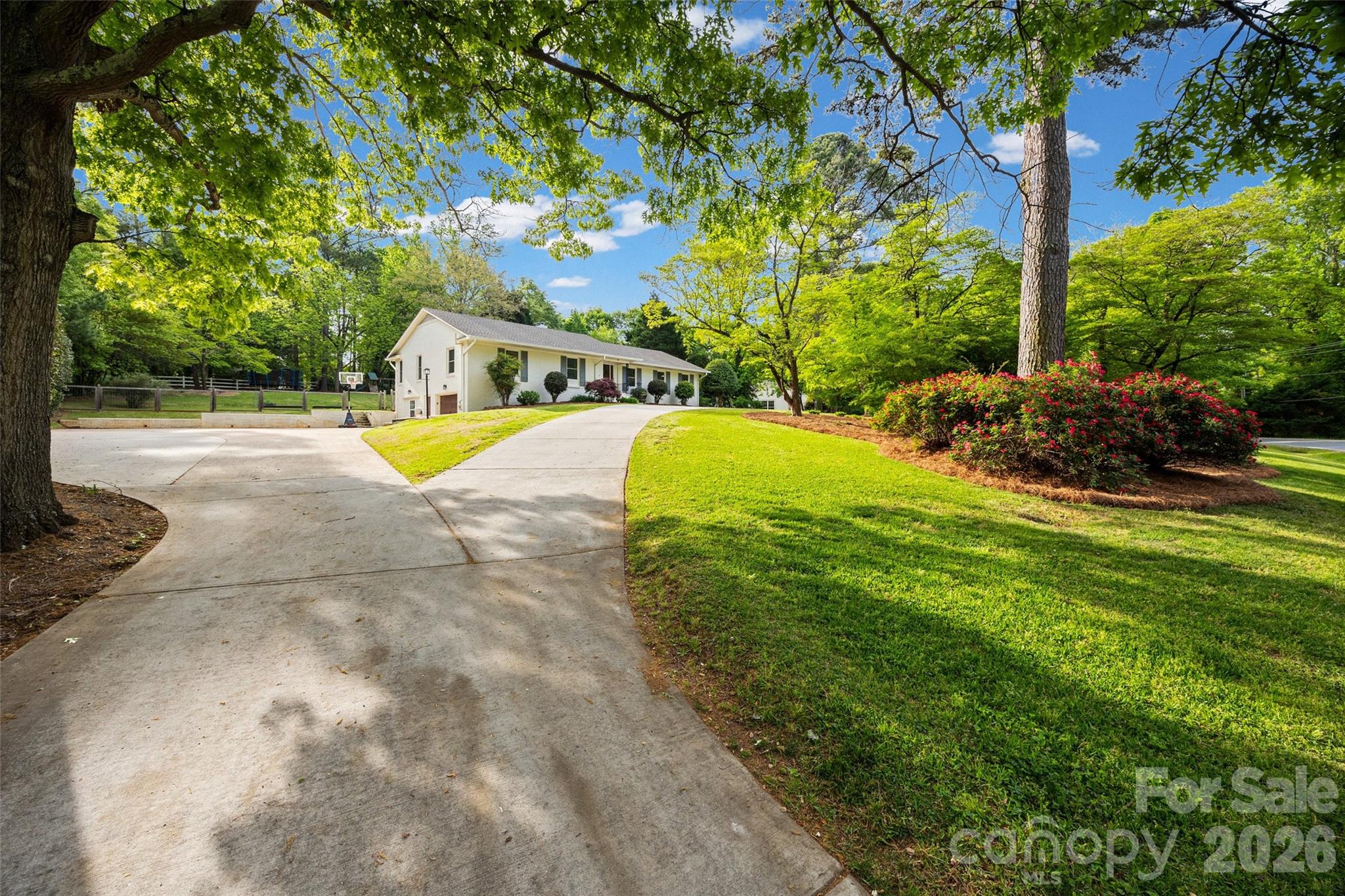 Welcome to a rare opportunity in the heart of Fort Mill – where timeless charm, generous space and thoughtful updates come together on a beautiful 1.11-acre lot. This classic brick ranch offers 3 bedrooms, 3 full baths, finished basement and more than 3,200 square feet of well-designed living space, all nestled in the desirable Fairway Drive neighborhood adjacent to the Fort Mill Golf Club.
Set among established homes and canopied by mature trees, this property embodies the character that only time can create. From the moment you arrive, the newly paved circular driveway and mature landscaping create an inviting first impression, with tall hardwood trees, flowering roses, dogwoods and expansive green space to provide both beauty and a sense of privacy.
Inside, natural light fills the home with peaceful views of the surrounding landscape. The primary suite has been extensively enhanced, featuring a beautifully updated bathroom, expanded closet space and custom built-ins. Additional bedrooms are generously sized and a finished basement provides an extra flex space ideal for a mother-in-law suite, media room, playroom, gym or private office.
Step outside to enjoy a sizable screened-in porch and custom designed outdoor lighting and landscaping that lets you enjoy your home well into the evening. The expansive backyard is a standout feature, with a custom stone patio, fire pit and built-in gas grilling station, offering endless possibilities for entertaining or simply enjoying the quiet beauty of a large backyard in the heart of Fort Mill.
With its prime location, mature surroundings and thoughtful updates, this home offers a unique blend of comfort, convenience and enduring character within minutes of everything Fort Mill has to offer and in one of the area’s most beloved and established neighborhoods.