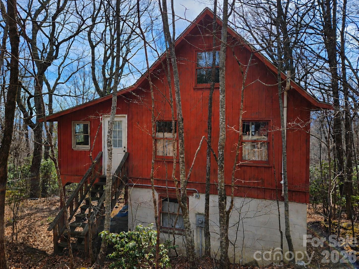 ROAD DAMAGED FROM RECENT RAINS NO DRIVE BYS!! Tucked away on top of the ridge, at the end of the road, this cabin offers 3.54 peaceful, private and gently sloping acres and is ready for a complete renovation. The existing structure provides a solid starting point, with a kitchen, dining area, and full bath on the main level (all need full renovation), and a large open bedroom/sitting space upstairs. Upper-level porches extend from two sides, where the previous owner began enclosing portions to increase living space while preserving an open area to capture the property’s view potential. With selective tree clearing—primarily below the home—the setting could open up to showcase long-range views. A small outbuilding offers additional storage or workshop possibilities. Property is being sold as-is and will require significant updates and improvements—ideal for investors or buyers looking to create a custom mountain retreat. *A new roof was installed after Hurricane Helene but no repairs were made to the damage inside of the home. Community note: STRs not allowed. AWD/4WD STRONGLY recommended... Please call before driving by!