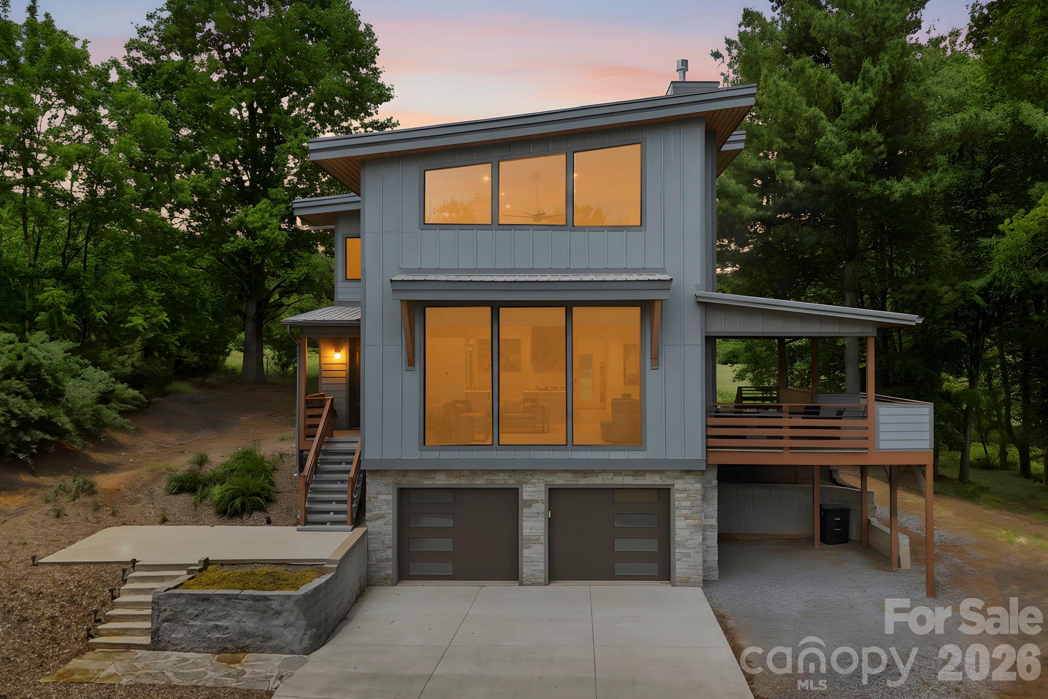 Modern mountain living combines with total privacy and convenience in this stunning Mills River retreat!  Situated on over an acre in a tranquil, pastoral setting, this sleek contemporary home offers the perfect blend of stylish design and easy access to the best of Asheville and Hendersonville. Enjoy nearby hiking and biking trails, breweries, and outdoor adventures while coming home to your own peaceful sanctuary.  The thoughtfully designed floor plan features open-concept living, dining, and kitchen spaces filled with natural light and designed for effortless everyday living and entertaining. The main level flows seamlessly onto a spacious covered porch, creating exceptional indoor/outdoor living space perfect for relaxing or hosting guests. A guest bedroom and full bath on the main level provide comfort and flexibility for visitors or multi-generational living.  Upstairs, the luxurious primary suite feels like a private retreat with a massive walk-in closet, and a spa-inspired bathroom featuring a soaking tub and walk-in shower with upscale finishes.  An added bonus upstairs is the flex space ideal for a home office, sitting area or reading nook.  The oversized basement garage offers abundant storage, workshop potential, and an EV charger for modern convenience. Throughout the home you'll be enamored by high-end finishes, clean architectural lines, and sophisticated modern styling that create a polished yet welcoming atmosphere.  Featured highlights include soaring vaulted ceilings, stunning quartz countertops, and European-style cabinetry.  This home presents a rare opportunity to combine a modern design, a spacious lot, and a prime Mills River location close to all the outdoor recreation, breweries, and amenities that make WNC so desirable.  Don't sleep on this opportunity, come see it for yourself!
