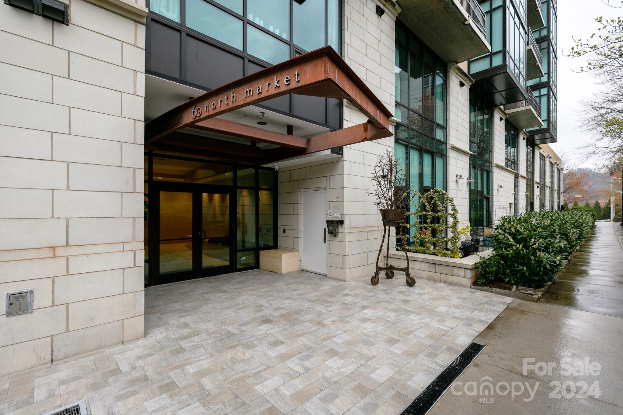 Be a part of Asheville's premiere downtown condo building, 60 N. Market Condominiums! This beautiful 1st floor condo has an open floor plan with a gas fireplace, bright dining nook and a wall of windows opening to a huge 200sf outdoor patio surrounded by trees. Wood floors, large closets with built-ins, laundry closet, stainless appliances and remote-controlled window coverings. Condo includes one dedicated parking space in the secure parking garage under the building. Owners share club room, outdoor patio with outdoor fireplace, common gas grill and fitness room. Condo is currently leased through November so is being sold fully furnished. Dues include cable, Internet, water and trash.
