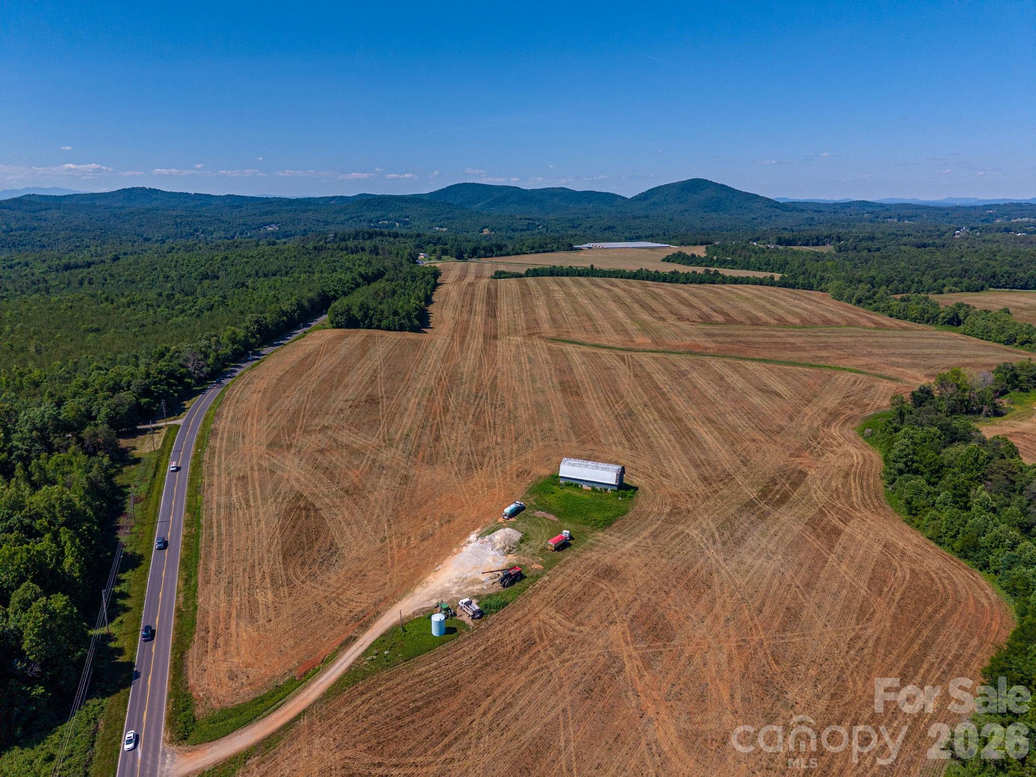 Rarely does a property of this caliber come to market. Spanning approximately 350+/- acres in the heart of Connelly Springs on Hwy 18 & Miller Bridge Road, this breathtaking tract offers a combination of beauty, productivity, and opportunity that is nearly impossible to find. Currently in row crop production, the land features gently rolling terrain, fertile Ag soils, and a creek winding through the property, creating both scenic appeal and valuable water resources. From multiple vantage points across the farm, enjoy stunning long-range mountain views that provide an unforgettable backdrop for a future homesite, equestrian estate, or working ranch. A large barn stands proudly on the property offering endless possibilities for restoration, livestock operations, or event space conversion.  With extensive road frontage, county water availability, excellent topography, and a highly desirable location, this property also presents significant investment potential. Whether your vision includes a working ranch, equestrian facility, poultry farm, private compound or event/wedding venue, the opportunities are as vast as the acreage itself. Properties offering this combination of scale, beauty, water features, productive farmland, mountain views, and future potential are exceedingly rare. Experience the freedom and possibilities that only a truly exceptional North Carolina farm can provide.