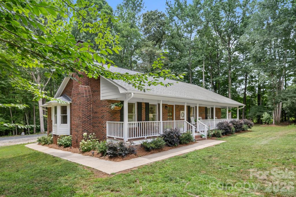 Tucked away on 3.88 beautiful acres, this charming full brick ranch offers the rare combination of privacy, acreage, and convenience. Surrounded by majestic oak trees and set well back from the road, the property provides a peaceful retreat with approximately half cleared land and half wooded, creating a picturesque setting rich with wildlife and natural beauty. Meandering trails wind through the wooded portion of the property, while fruit trees, blackberry bushes, and a tranquil fish pond with an arbor, picnic table, and planter create inviting spaces to relax, explore, and enjoy the outdoors. Inside, you’ll find hardwood floors throughout the main living areas and bedrooms, updated bathrooms, a spacious laundry room, dedicated office, and a welcoming kitchen designed for everyday living. A reverse osmosis water filtration system at the kitchen sink provides fresh, purified drinking water. The expansive farmer’s rocking chair front porch is the perfect place to enjoy your morning coffee or unwind while taking in the peaceful surroundings. With no HOA, the possibilities are endless. Whether you dream of a mini farm, gardening, raising chickens, or having a horse or two, this property offers the space and flexibility to make it happen. A charming vintage barn provides exceptional versatility as a garage, workshop, barn, storage space, or hobby area, while adding timeless character to the property. A separate chicken coop is already in place, making it easy to embrace country living from day one. Enjoy the peace of country living just 2 miles from charming downtown Waxhaw, approximately 3.5 miles from Wesley Chapel shopping and dining, and only 15 to 20 minutes from I-485, providing easy access to Charlotte while allowing you to come home to your own private retreat. Located outside municipal limits, you’ll enjoy the benefit of county taxes only with no city taxes.