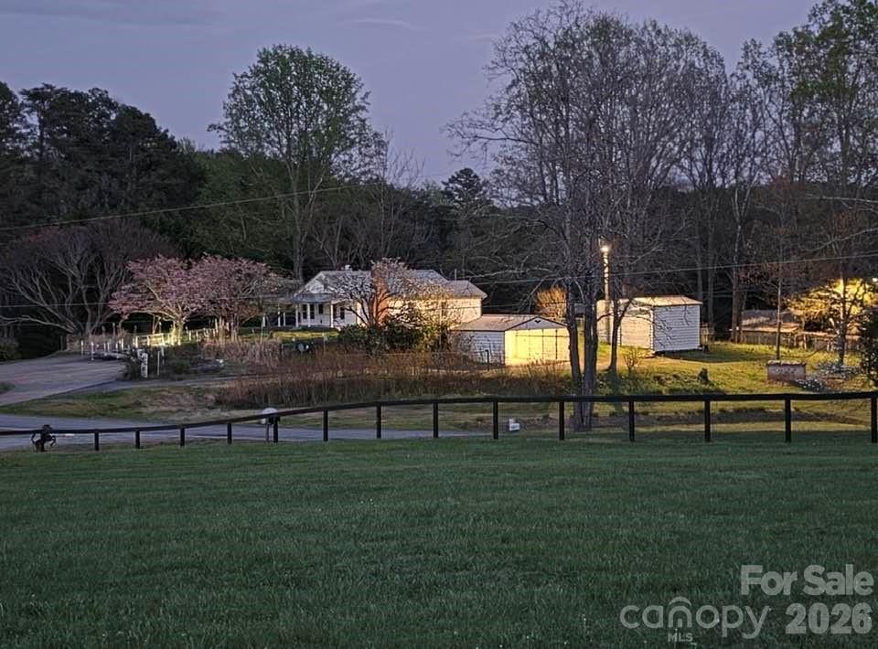 This charming 1950s hobby farm is nestled on 2.80 acres in Polk County, NC and offers the perfect blend of peaceful country living and convenient access to town and major highways. Perched atop a gentle hill, this 1,031 sf farmhouse enjoys year-round mountain views, while overlooking a picturesque horse farm. The classic wraparound porch invites you to sit a spell and enjoy the quiet surroundings before stepping inside this cozy home! The living room is complete with warm cedar paneling and a propane glass-rocks fireplace. From there, the home flows easily into the updated kitchen and dining area or toward the 2 small bedrooms, both bedrooms maintaining the home’s original charm (without built-in closets). Previous owner used one room as a bedroom and the other as a large walk-in closet. A number of home improvements have been completed since 2020 to enhanced the home while preserving its vintage character. Additional features include a wood-burning stove in the unfinished basement/crawlspace area, newer garage doors with remote controls, fenced yard around the house, transferable CPI security system, and attic storage space. The land has long been enjoyed for farming and homesteading, with a ready-to-use garden area, mature blueberry and blackberry bushes, fig trees, roses, and plenty of room to spread out and enjoy the outdoors. Multiple outbuildings, storage sheds, animal shelters, an attached 2-car garage, and a 2-car carport make this property ideal for hobby farming, gardening, or simply embracing a slower pace of life. This property currently shares a well and generator with the cabin behind the house, (owned by same seller). That property will soon be marketed separately, and so the seller is in the process of getting a new power meter placed at the adjoining cabin, but intends to convey both with the shared well. Whether you’re dreaming of a hobby farm, mini homestead, mountain retreat, or quiet country getaway, this special property offers timeless charm in the beautiful foothills of western North Carolina. Shown by appointment only!  PLEASE...DO NOT GO DOWN TO THE CABIN BEHIND THIS HOUSE...IT IS NOT PART OF THIS SALE!