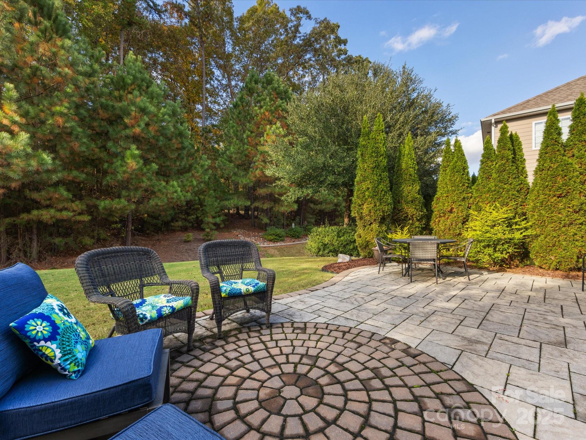 PRIVATE BACKYARD!  Lovely transitional 2-Sty situated on a level lot w/Guest BR (#5) on the main level!  Formal LR and DR. Gourmet KT features SS double oven, microwave, gas range, granite counters and tile backsplash, island, pull-out shelving and trash in lower cabinet. KT is open to the FR w/gas FP. Wood flooring on main level with tile in baths and mud room. 3-Car GAR features an 'electric vehicle plug'. Extended brick patio and mature landscaping. Level 2 features a Primary Suite w/Sitting Rm, double closets, an impressive spa-like bath w/separate vanities, garden tub and shower; as well as BR's #2, #3, #4 - 2 Full BAs, and a large Bonus Rm. ADT security system features cameras on the Front Porch, Family Rm, Doorbell and Rear Corner. Fiber cement and stone siding. Community features include a Club House, Fitness Center, Playground, Recreation Area, Tennis Court(s), Walking Trail & Pool. Close proximity to restaurants and shopping. Fort Mill School system! You'll love living here!